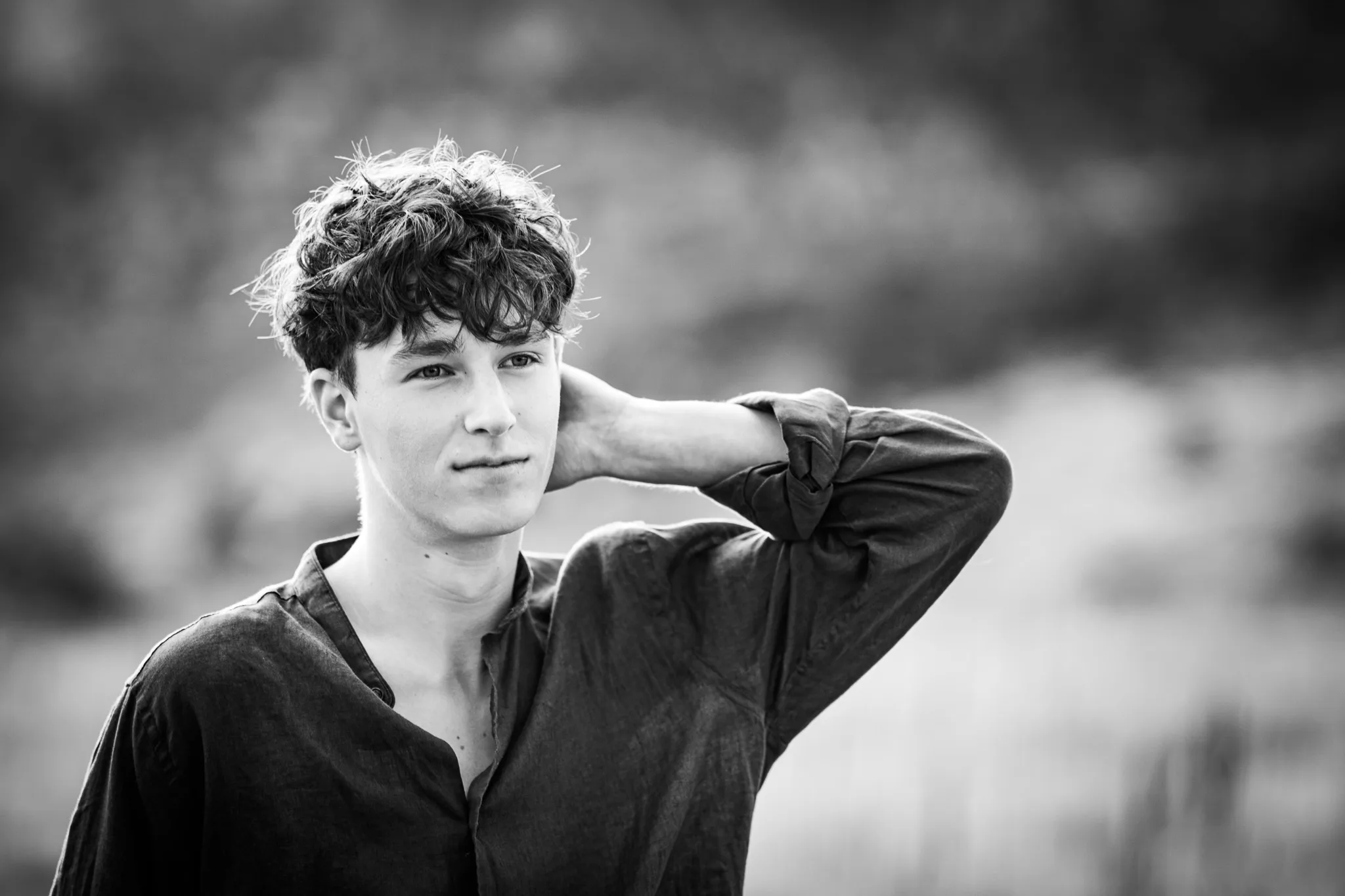 Black and white portrait of Arlo, one hand behind his neck, gazing past the camera.