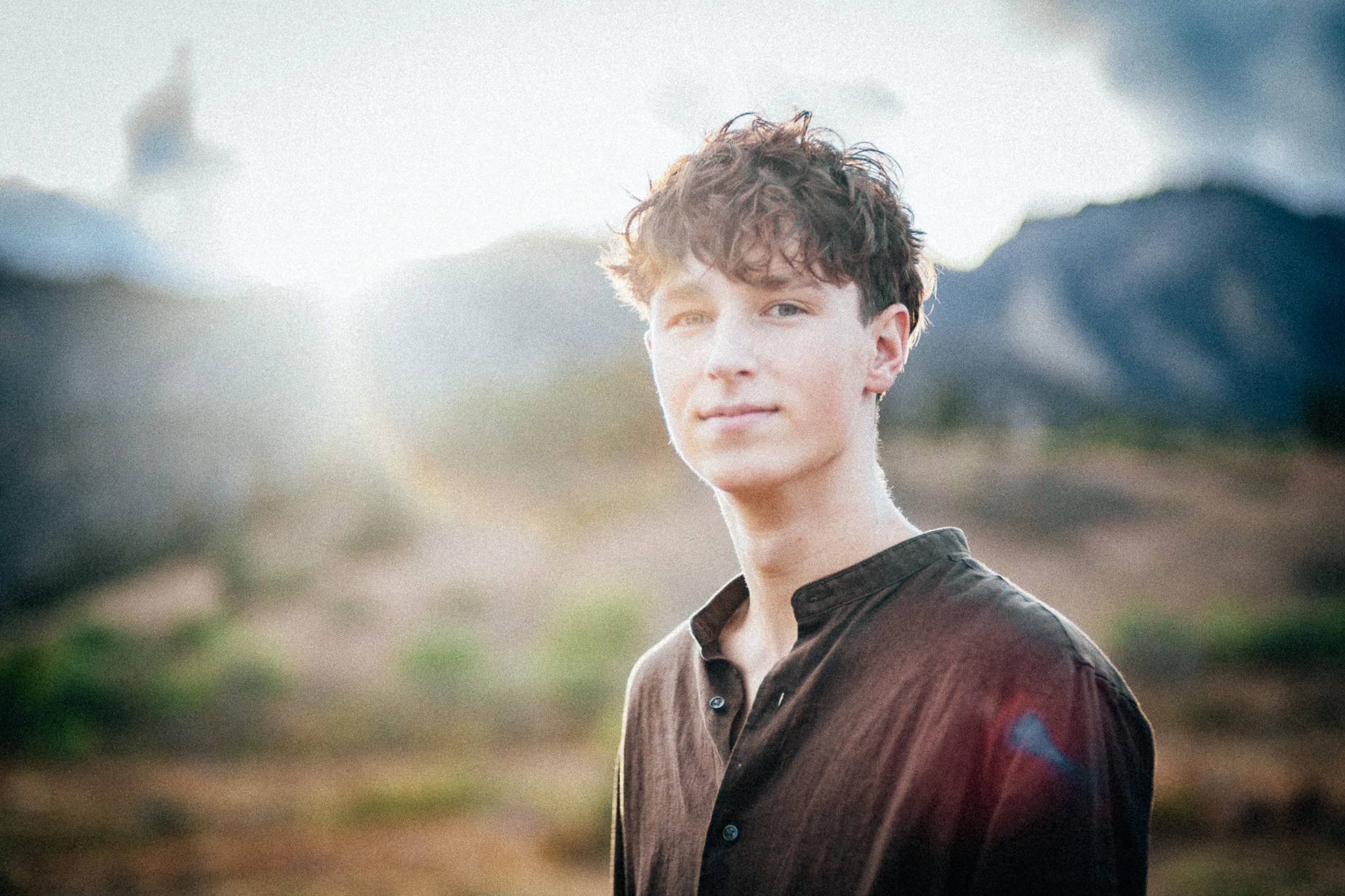 Arlo looks toward the camera as the low sun flares across the frame, mountains behind.