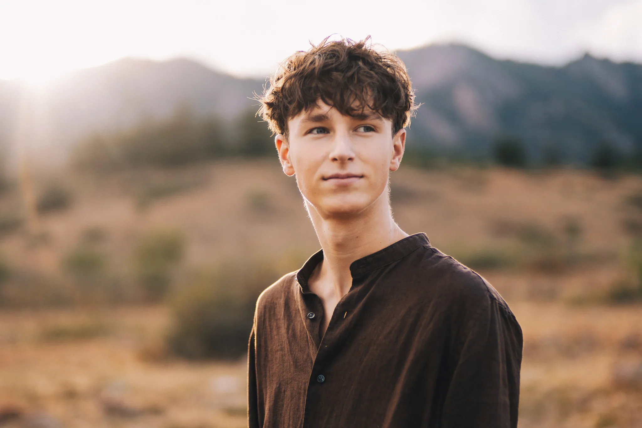 Arlo glances past the camera in soft golden backlight, the foothills blurred behind him.