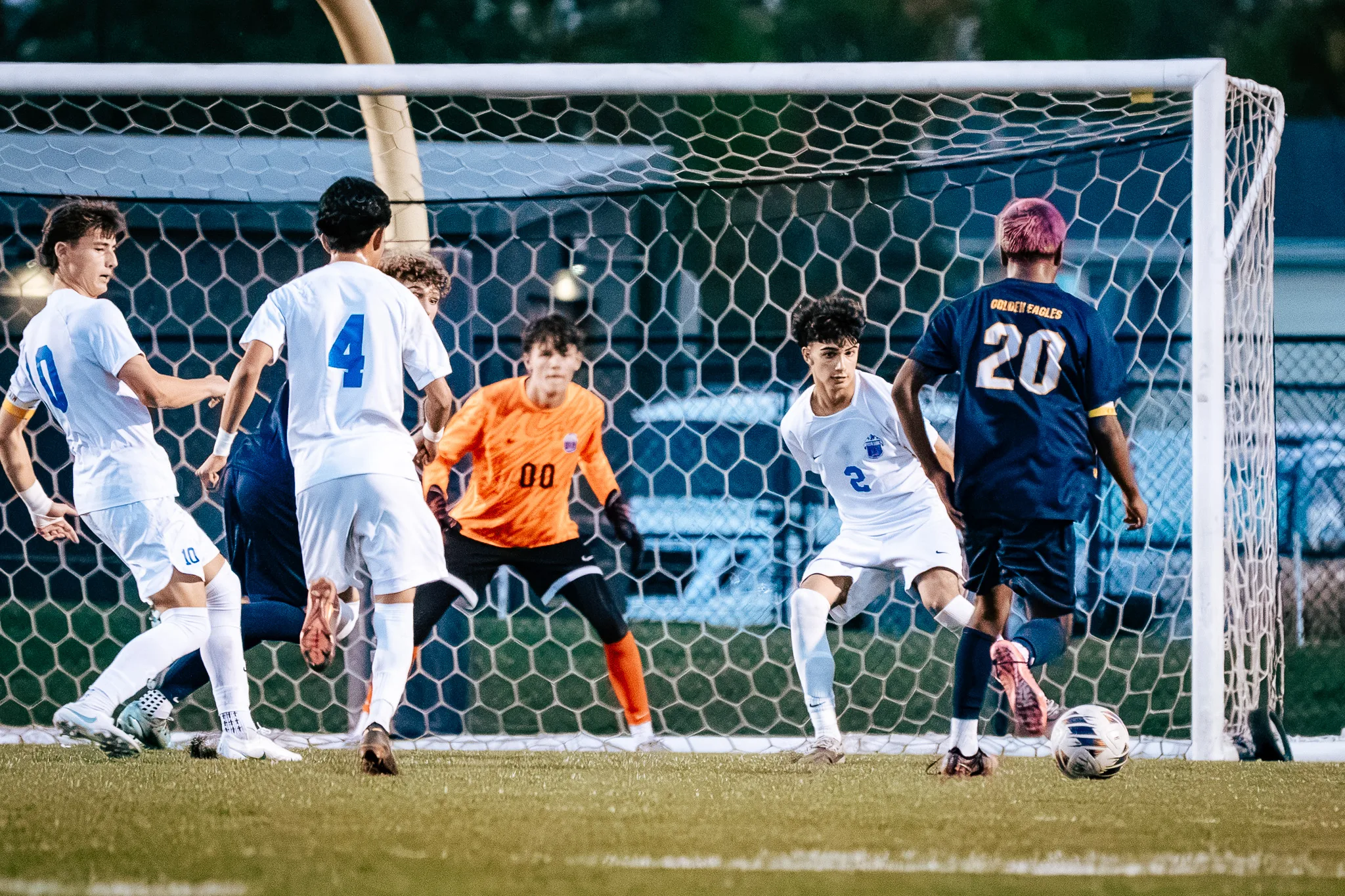 Frederick number 20 runs at the goal with the ball as the Centaurus goalkeeper in orange, number 00, crouches ready and Centaurus numbers 4 and 2 scramble to defend