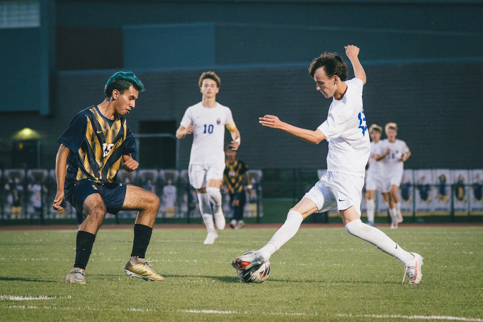 Frederick number 15 squares up to a Centaurus player with a foot on the ball while Centaurus number 10 waits behind them