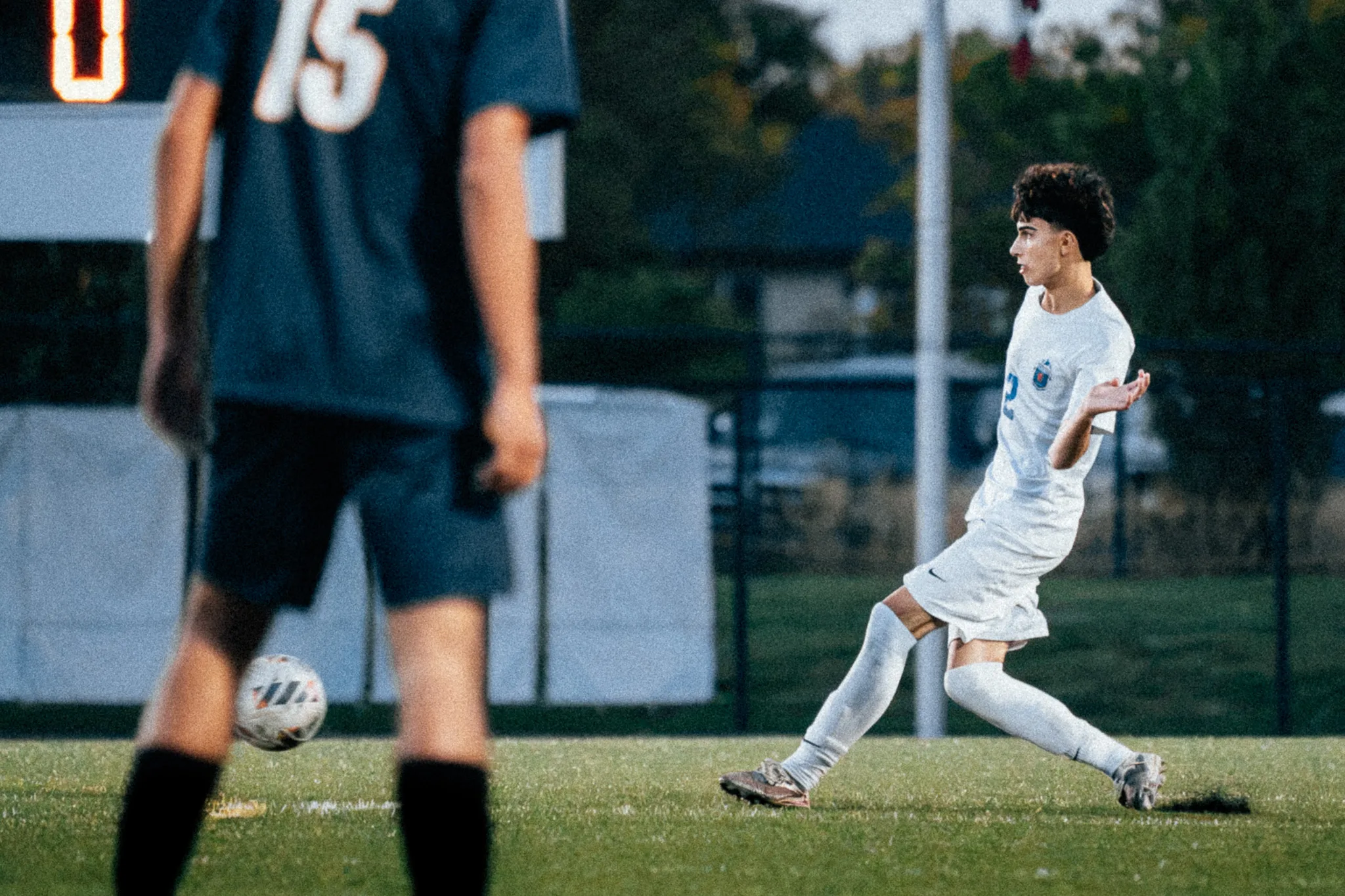 Centaurus number 2 sends the ball past Frederick number 15, who stands blurred in the foreground with his back to the camera