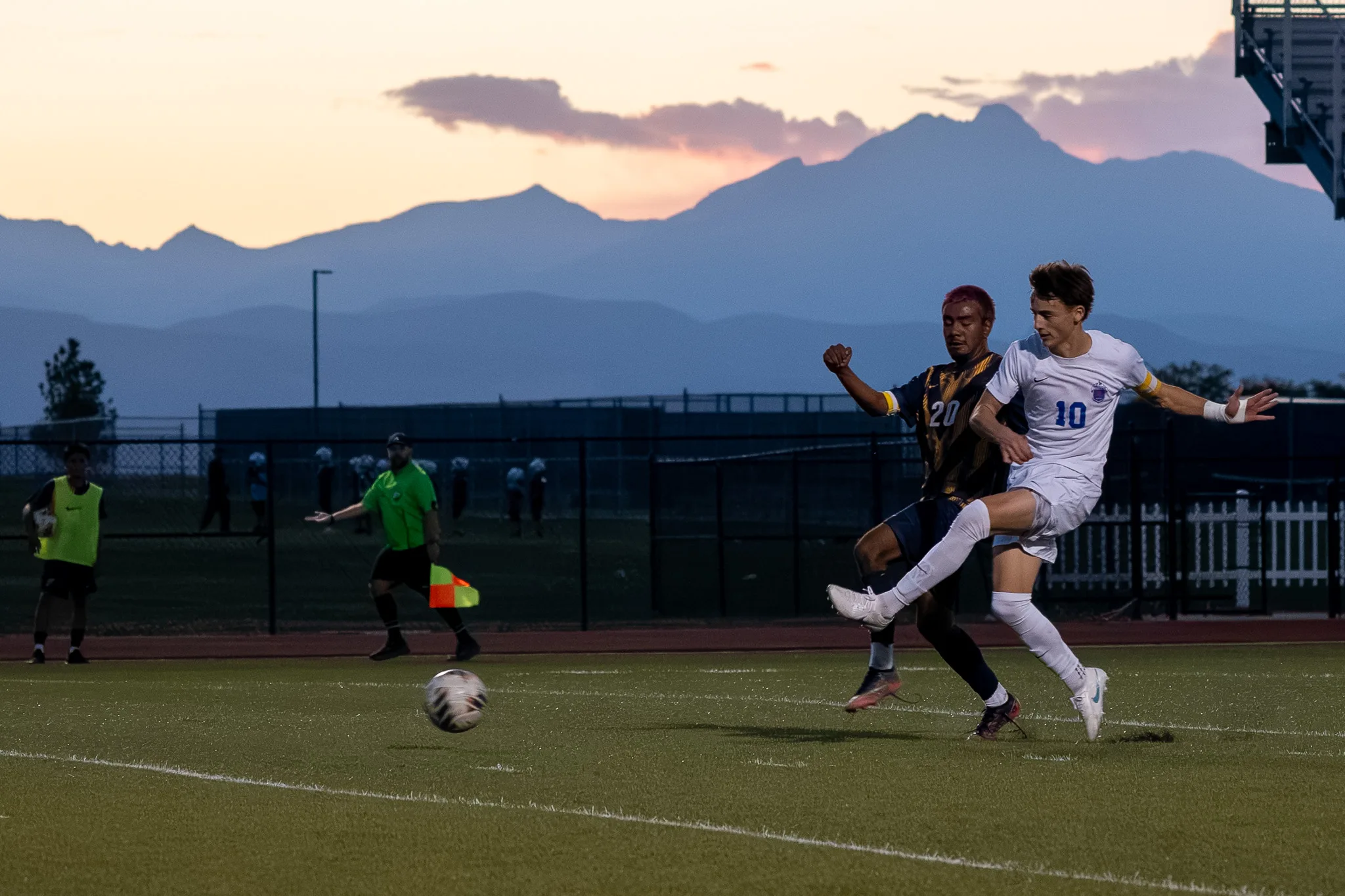 Centaurus number 10 swings his leg through the ball as Frederick number 20 stays tight behind him, the mountains darkening beyond