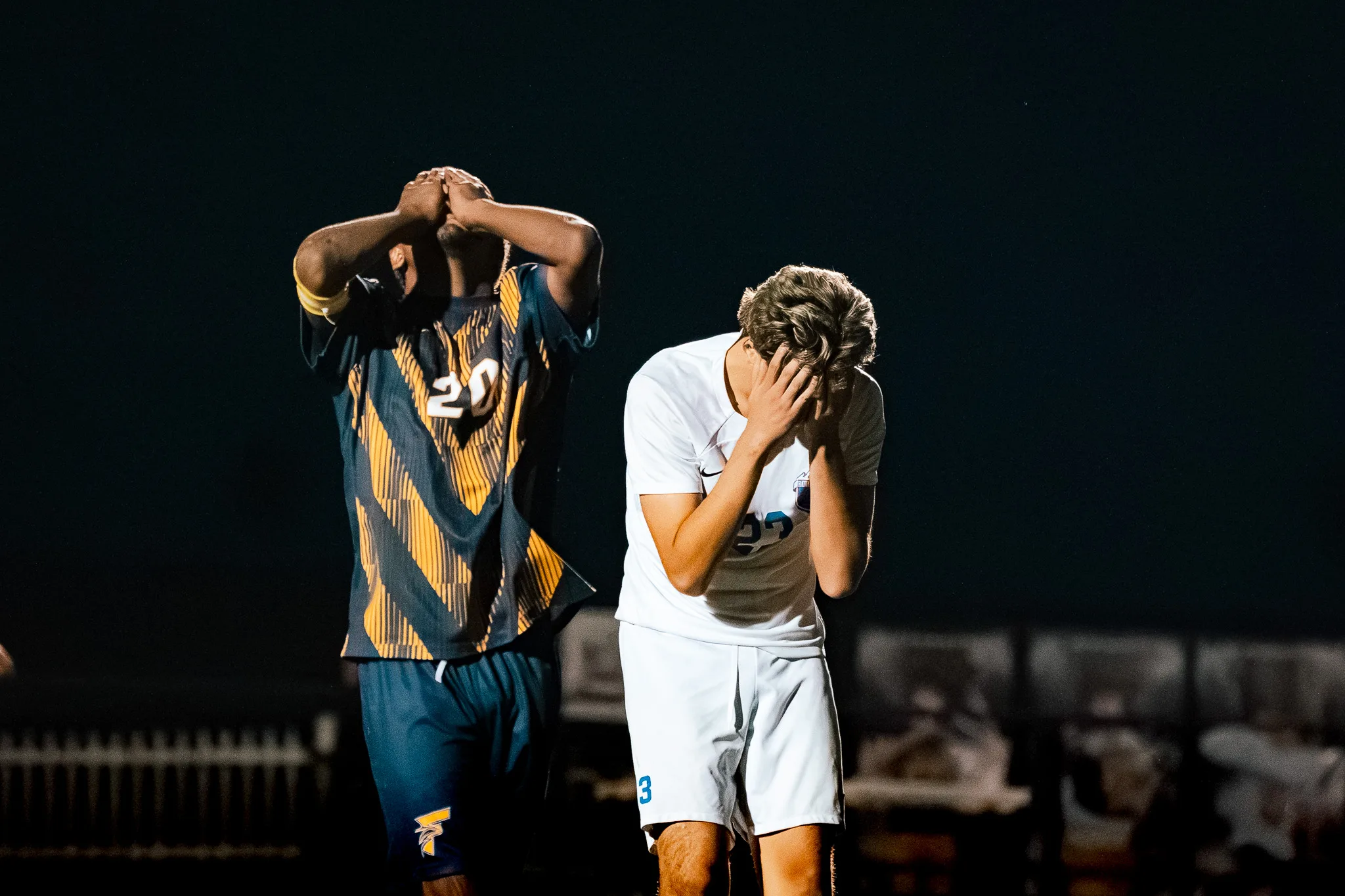 Frederick number 20 and a Centaurus player stand apart in the dark, each with his hands pressed to his face