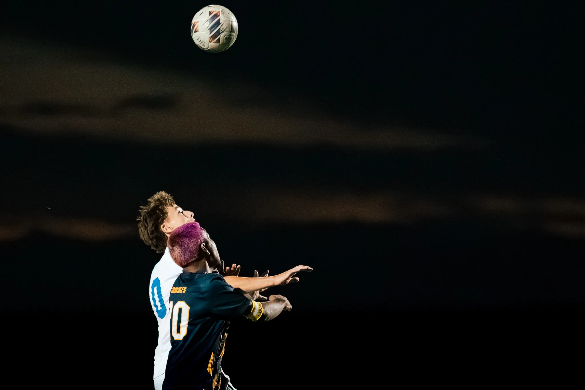 Against a black sky, Frederick number 20 and a Centaurus player rise together for a header, the ball high above them