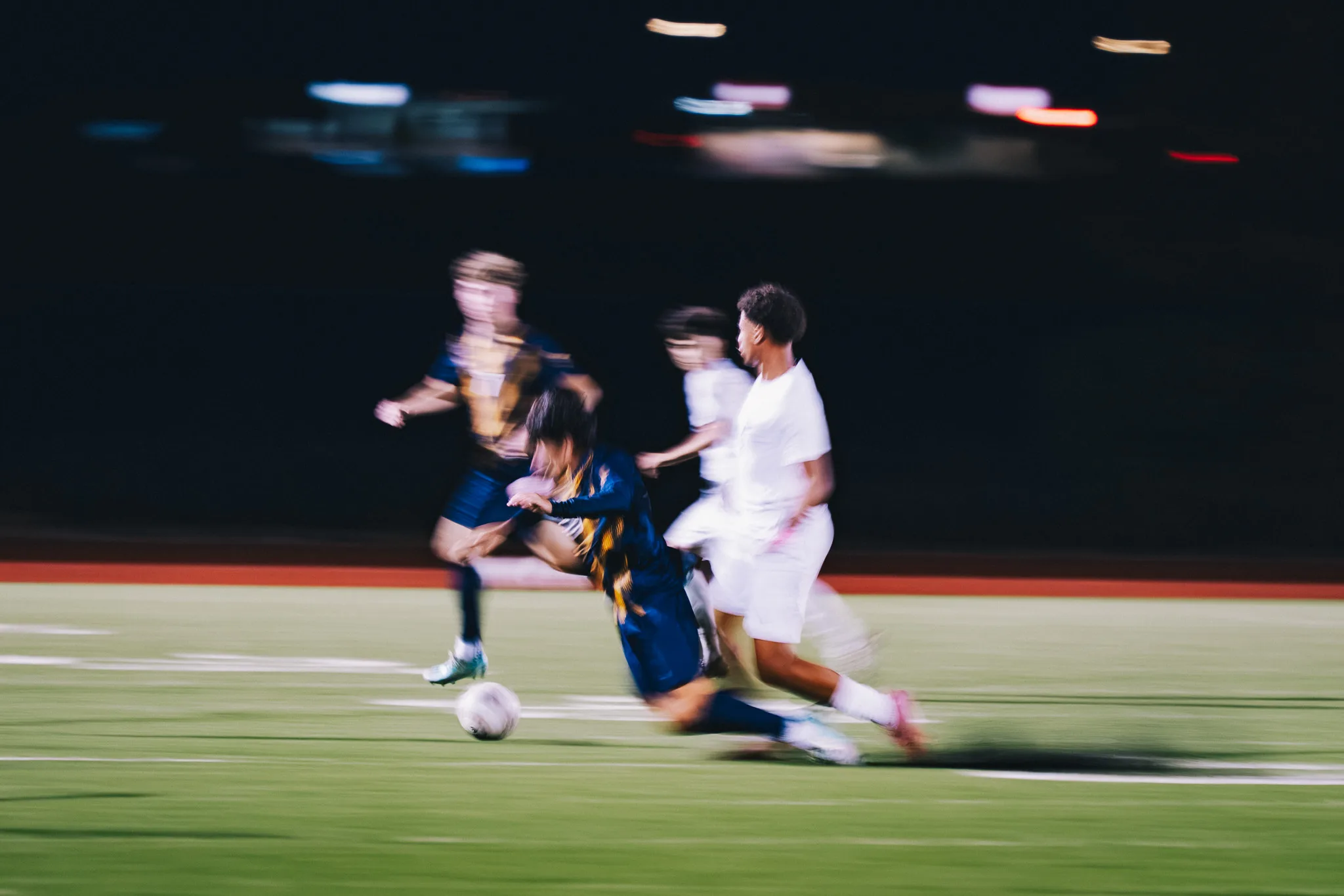 In a blur of motion, a Frederick player pitches forward toward the turf as a Centaurus player runs past him, the ball rolling at the left