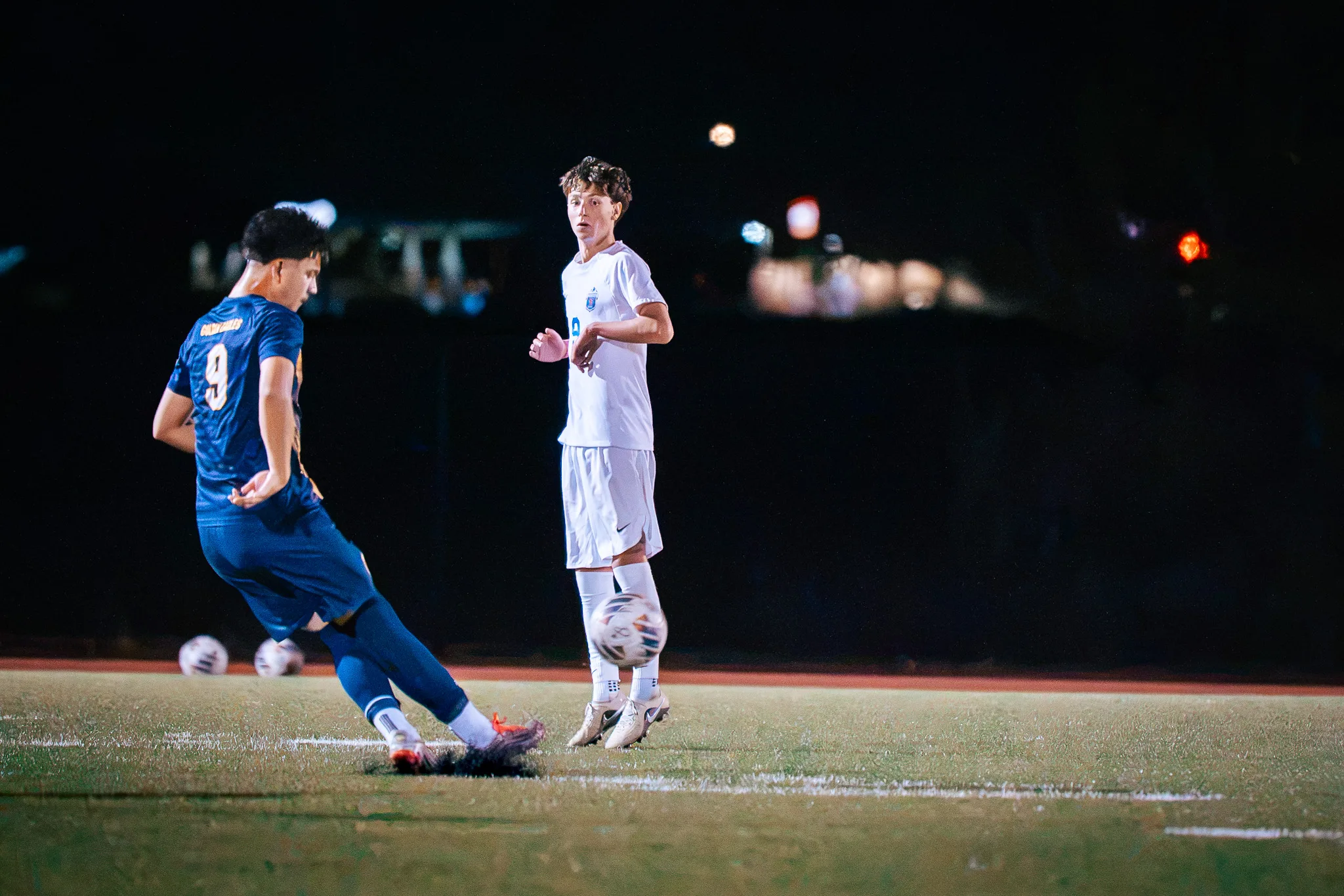 Frederick number 9 strikes the ball at night as a Centaurus player looks on, spare balls lying in the grass behind them