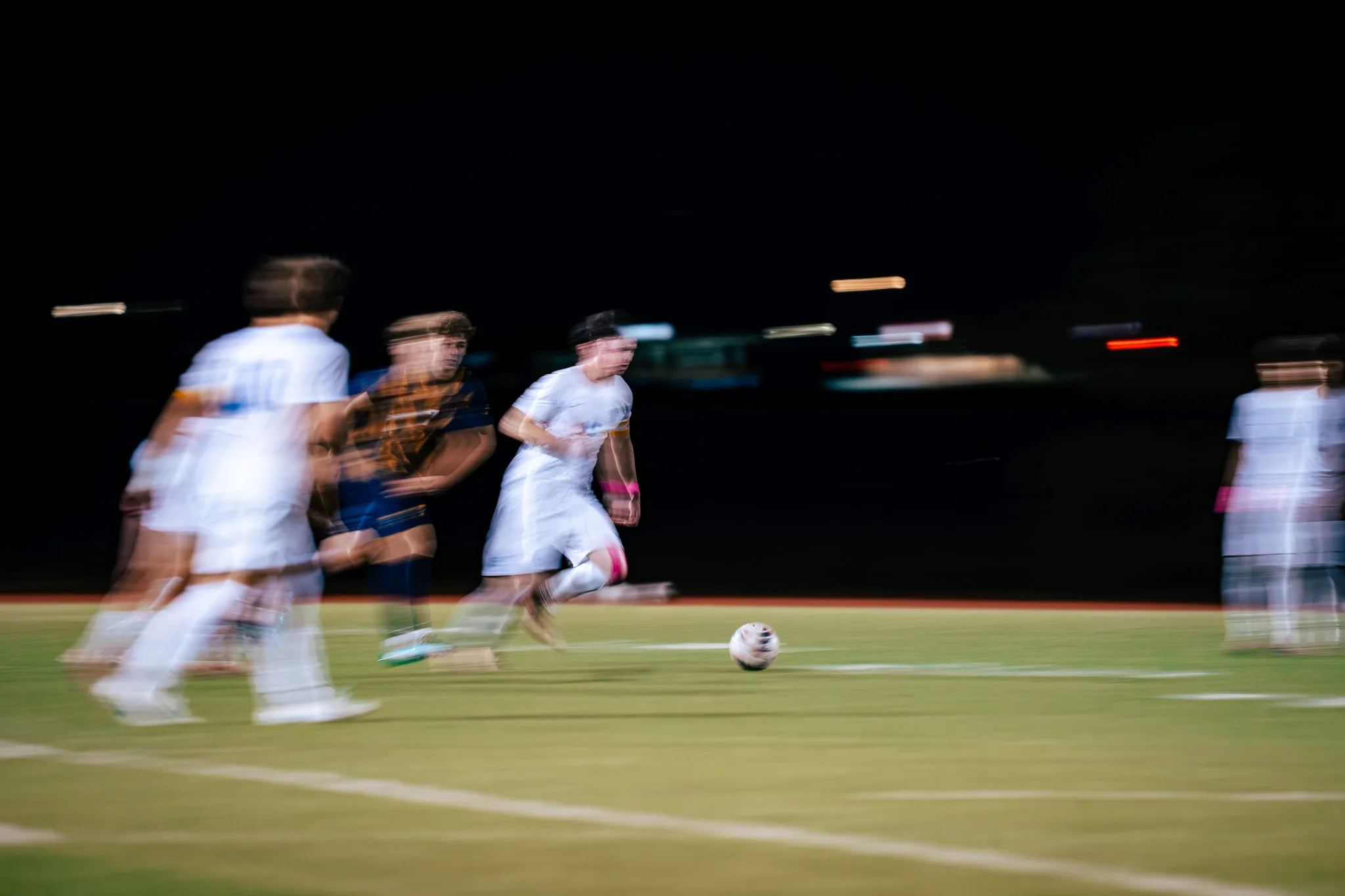 In a streak of motion, a Centaurus player dribbles ahead of a Frederick player as teammates blur past on both sides