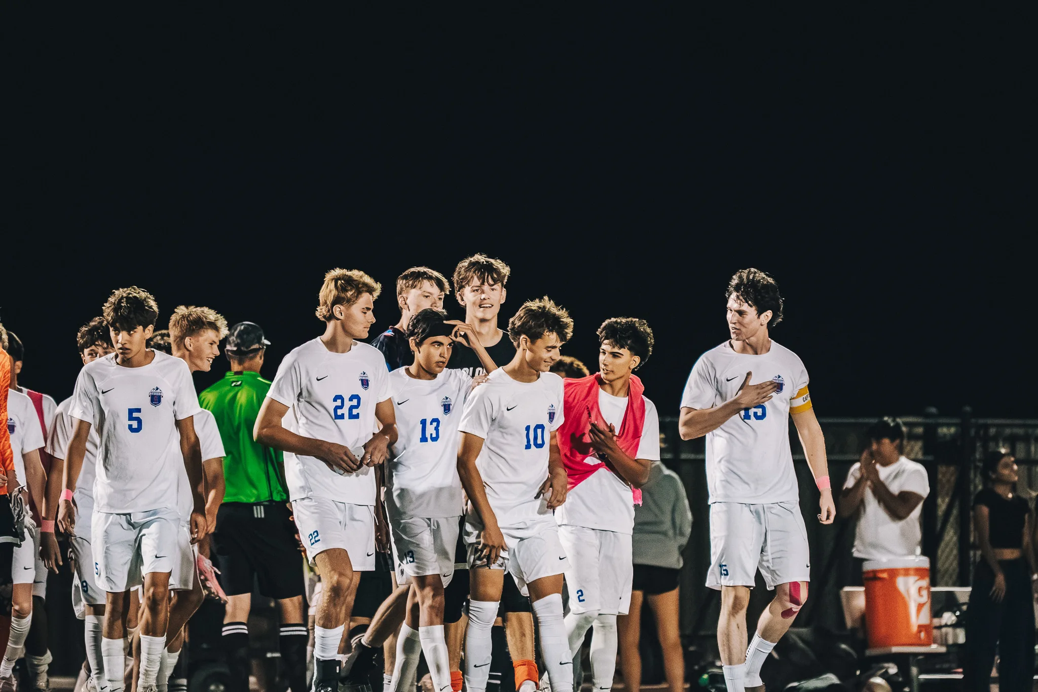 Centaurus players walk together along the sideline, numbers 5, 22, 13 and 10 among them, number 15 resting a hand on his chest as a referee in green walks behind
