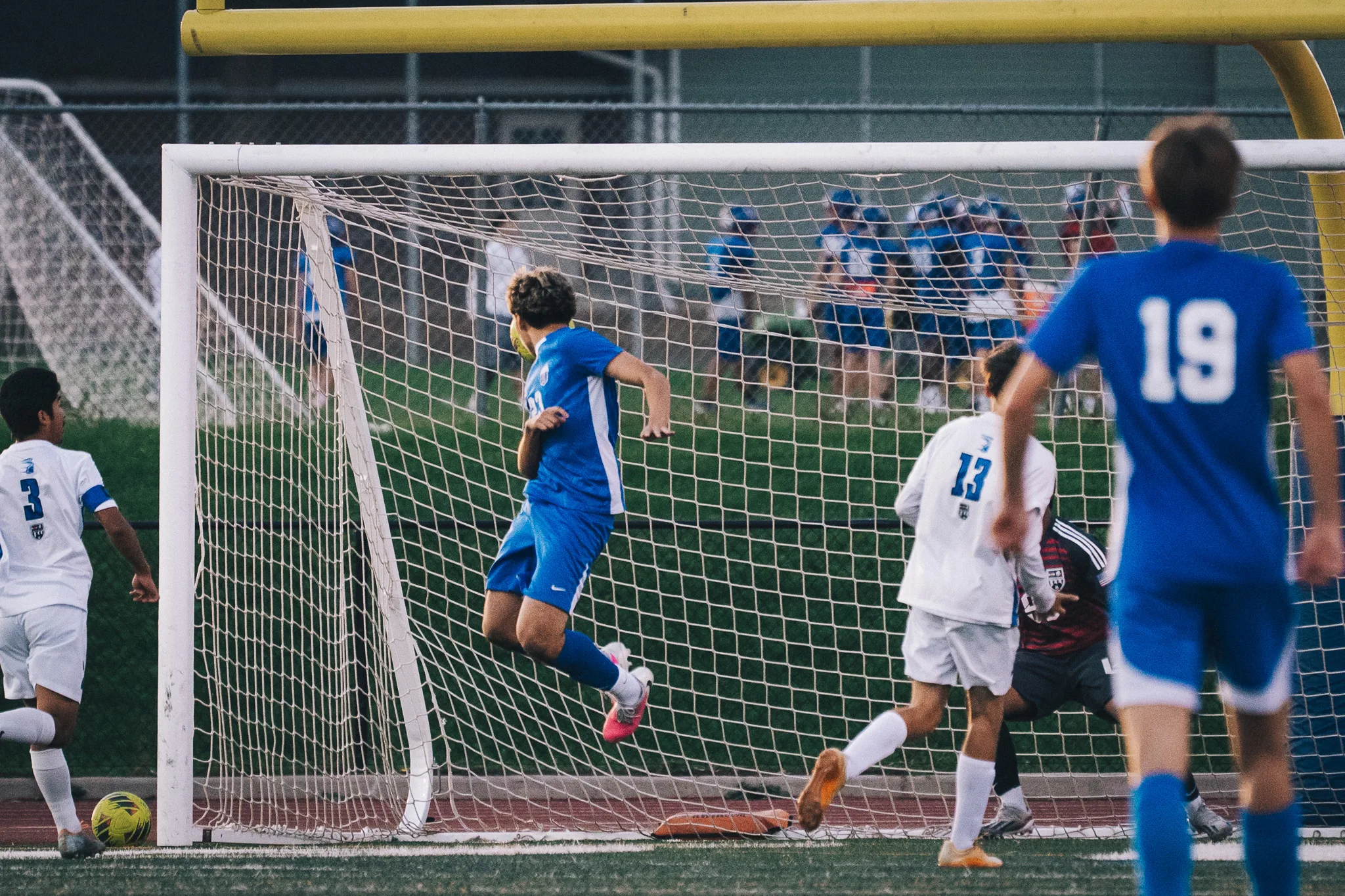 In front of the goal, a Centaurus player leaps with the ball beside his head, Longmont number 13 and the Longmont goalkeeper close by