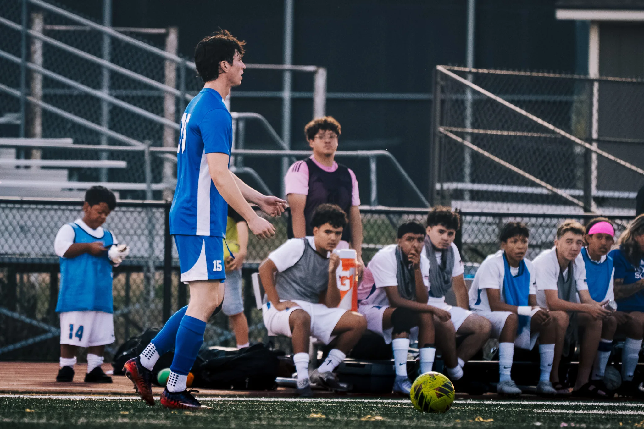 With the ball on the turf nearby, Centaurus number 15 strides along the sideline, the Longmont bench behind him
