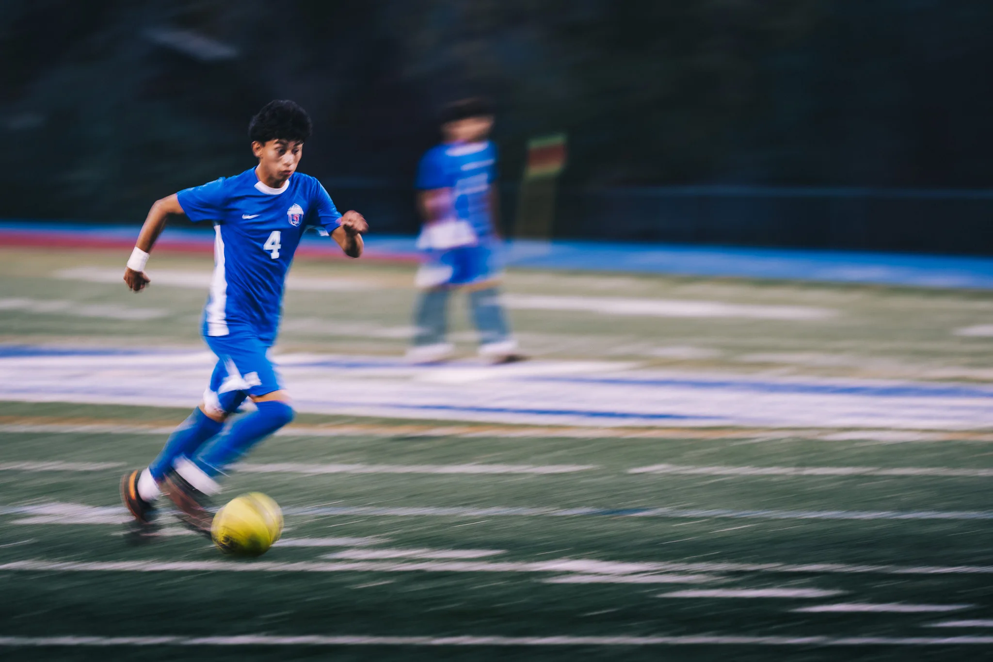 At full speed, Centaurus number 4 dribbles through a motion blur, a teammate soft in the background
