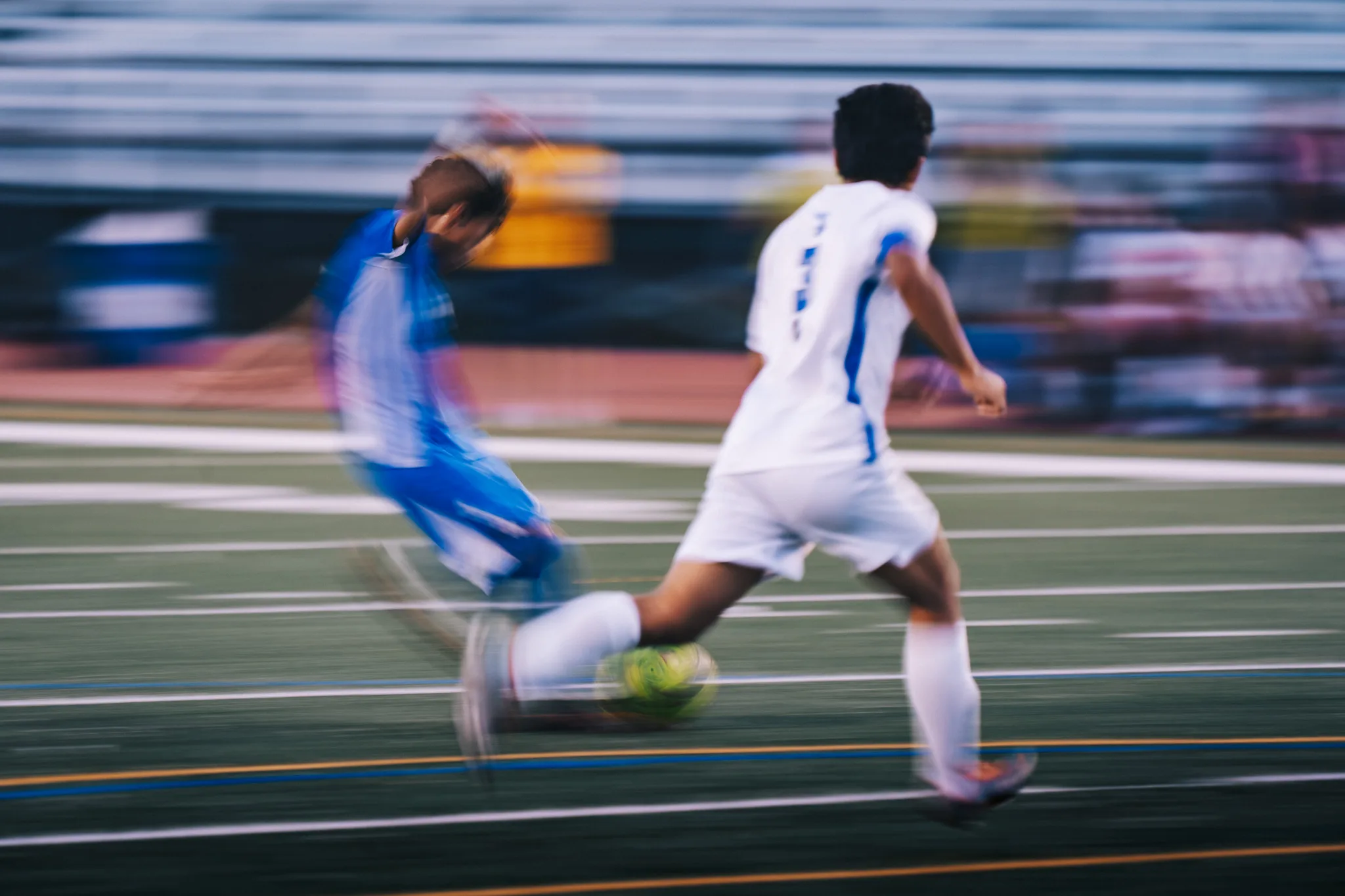 The bleachers blur behind a Longmont player and a Centaurus player as they race for the ball