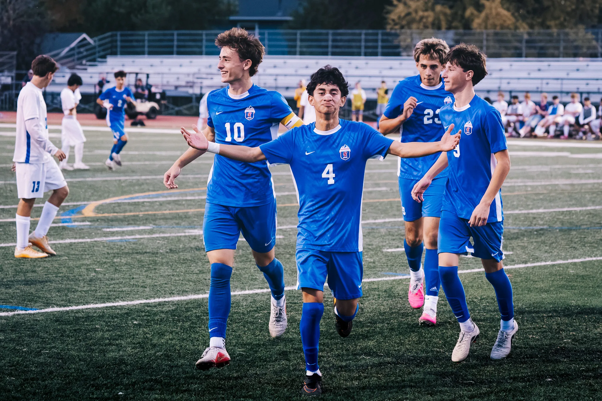 Centaurus number 4 jogs toward the camera with his arms out as teammates, including numbers 10 and 23, celebrate with him