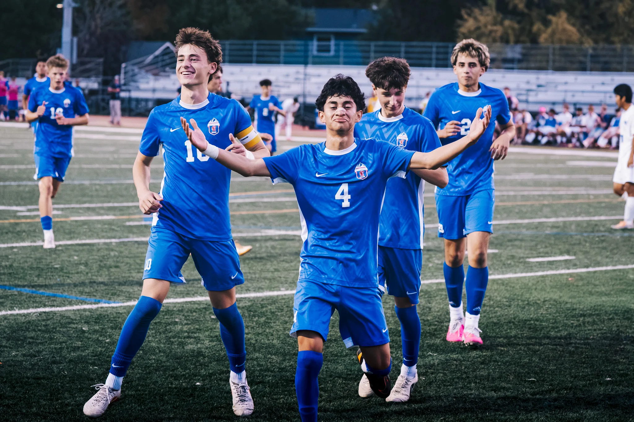 Arms spread wide, Centaurus number 4 celebrates as smiling teammates follow him