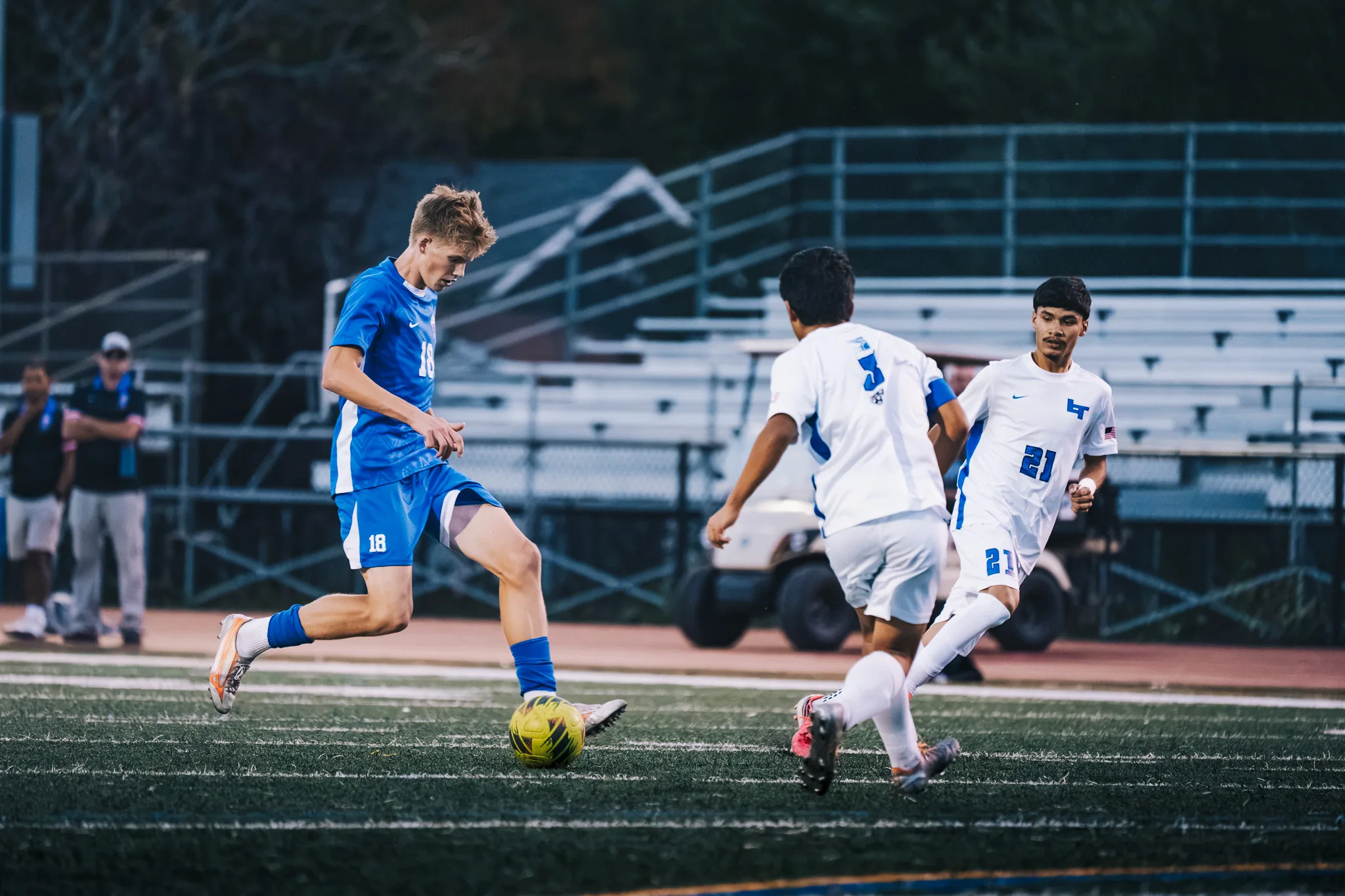 Centaurus number 18 dribbles toward Longmont numbers 3 and 21 as they close in, the bleachers behind them