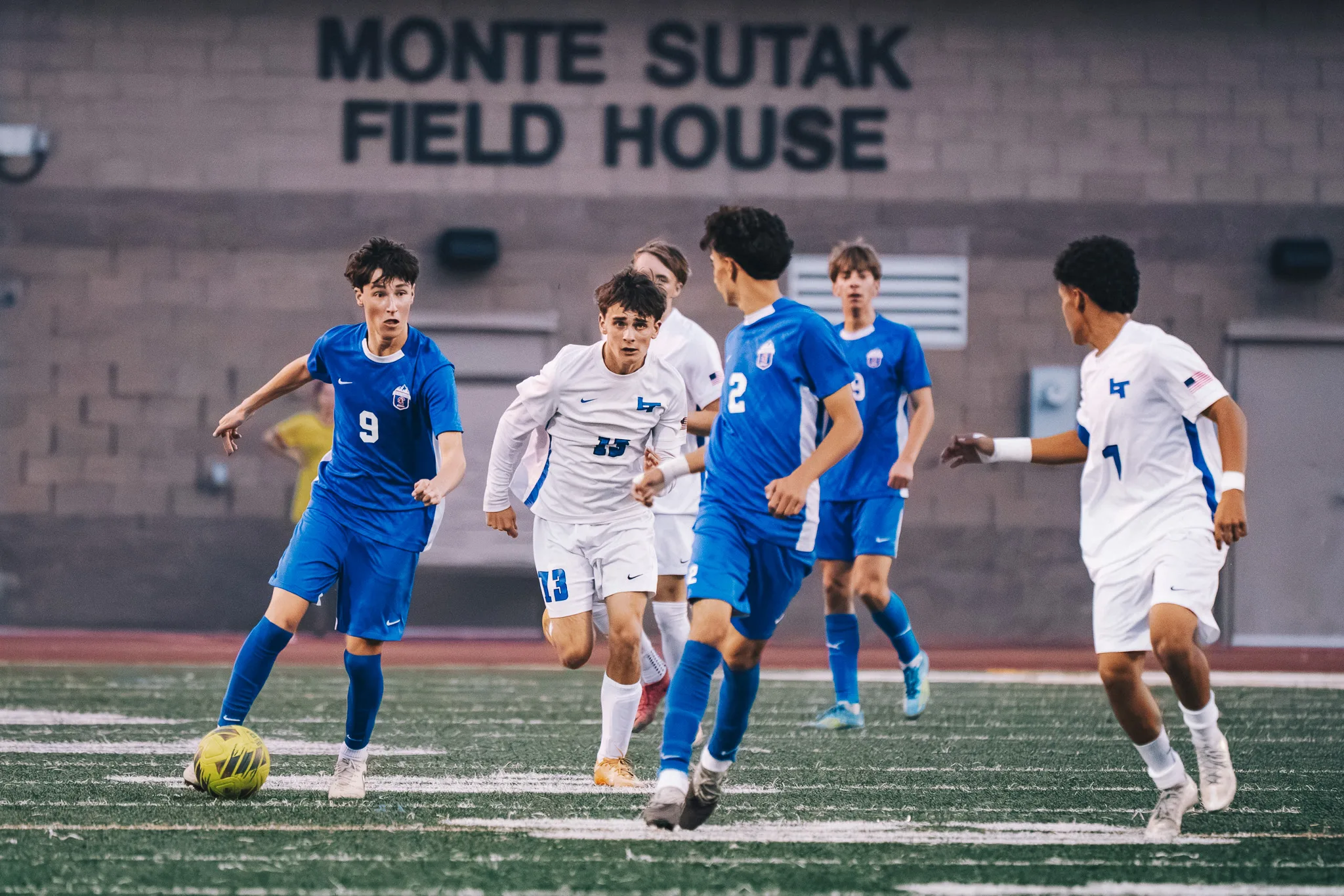 Centaurus number 9 dribbles with Longmont number 13 running at him, Centaurus number 2 and others nearby