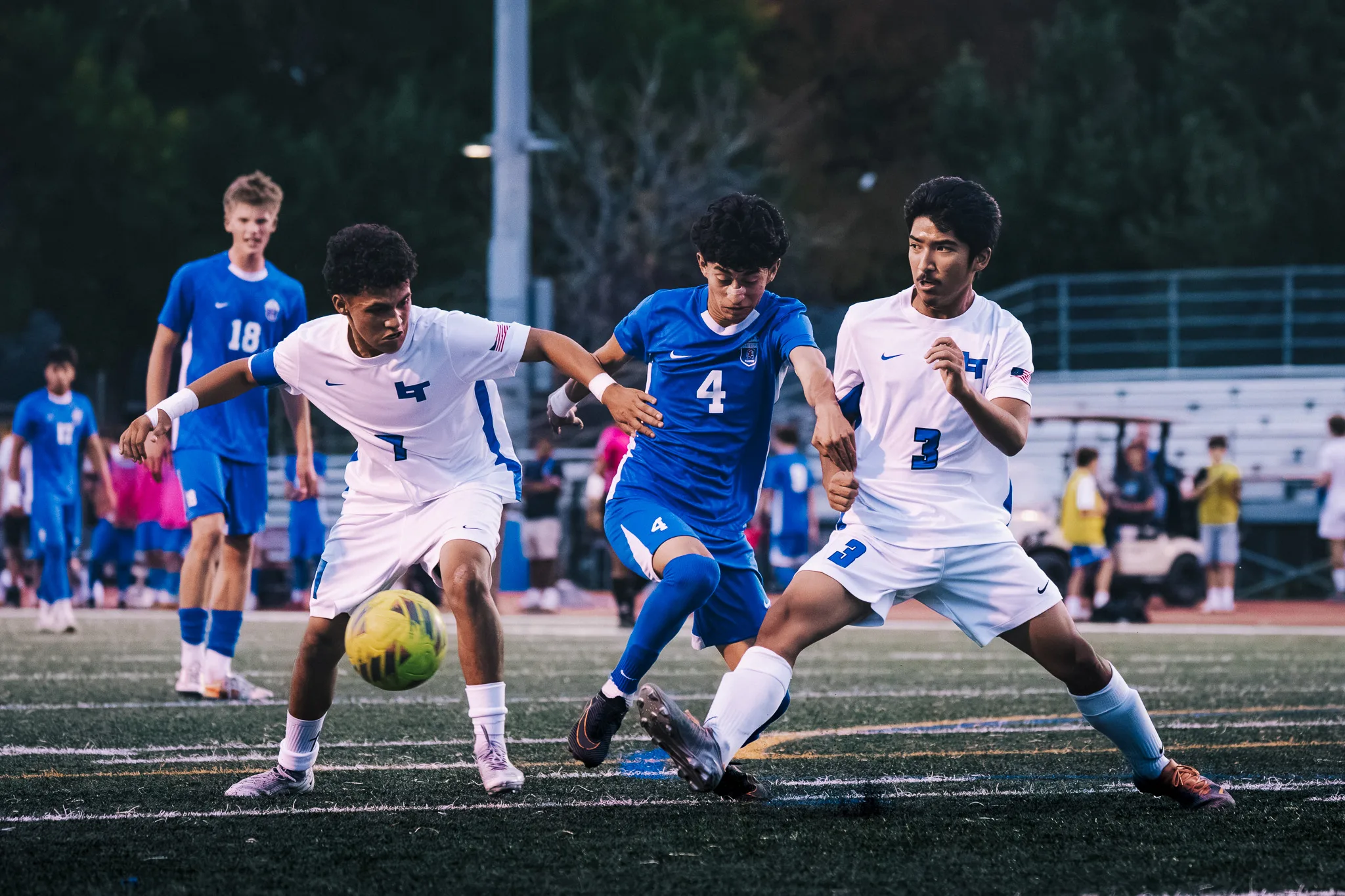 In a scramble for the ball, Centaurus number 4 is pressed between Longmont numbers 7 and 3 while Centaurus number 18 watches