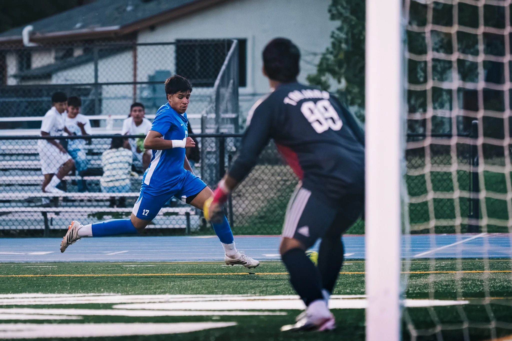 The Longmont goalkeeper, number 99, crouches in front of the goal as Centaurus number 17 runs toward him