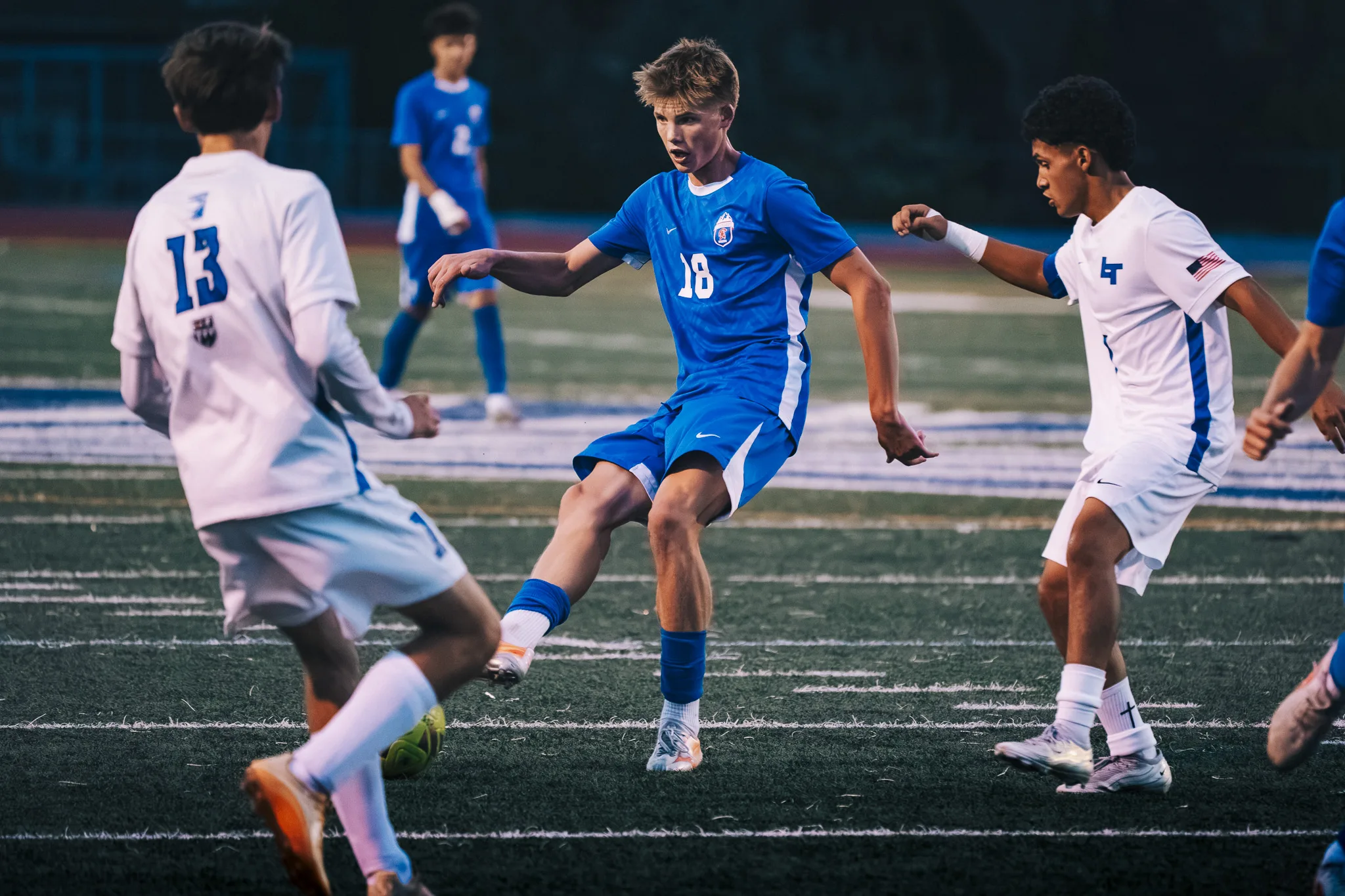 Centaurus number 18 stretches a foot toward the ball as Longmont number 13 and another Longmont player move in