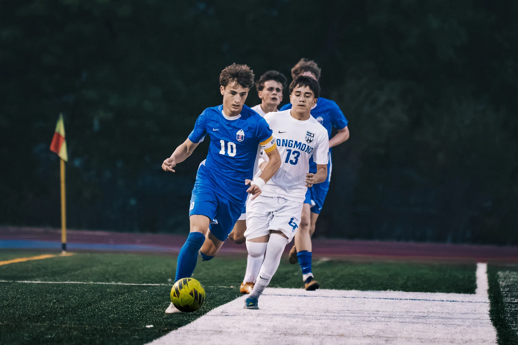 Near the edge of the field, Centaurus number 10 dribbles the ball with Longmont number 13 right beside him