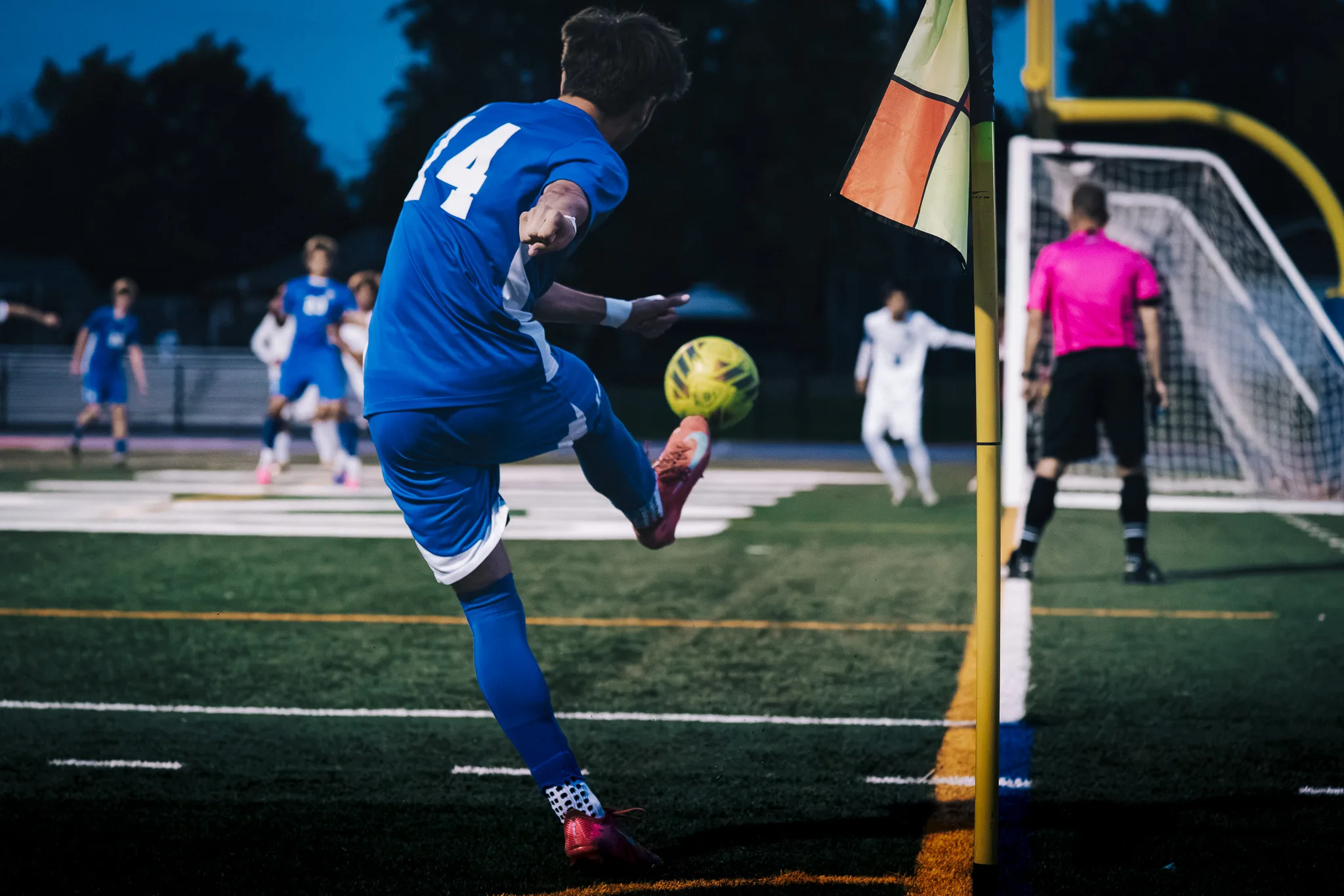 On a corner kick, Centaurus number 14 sends the ball into the air as an official in pink waits by the goal