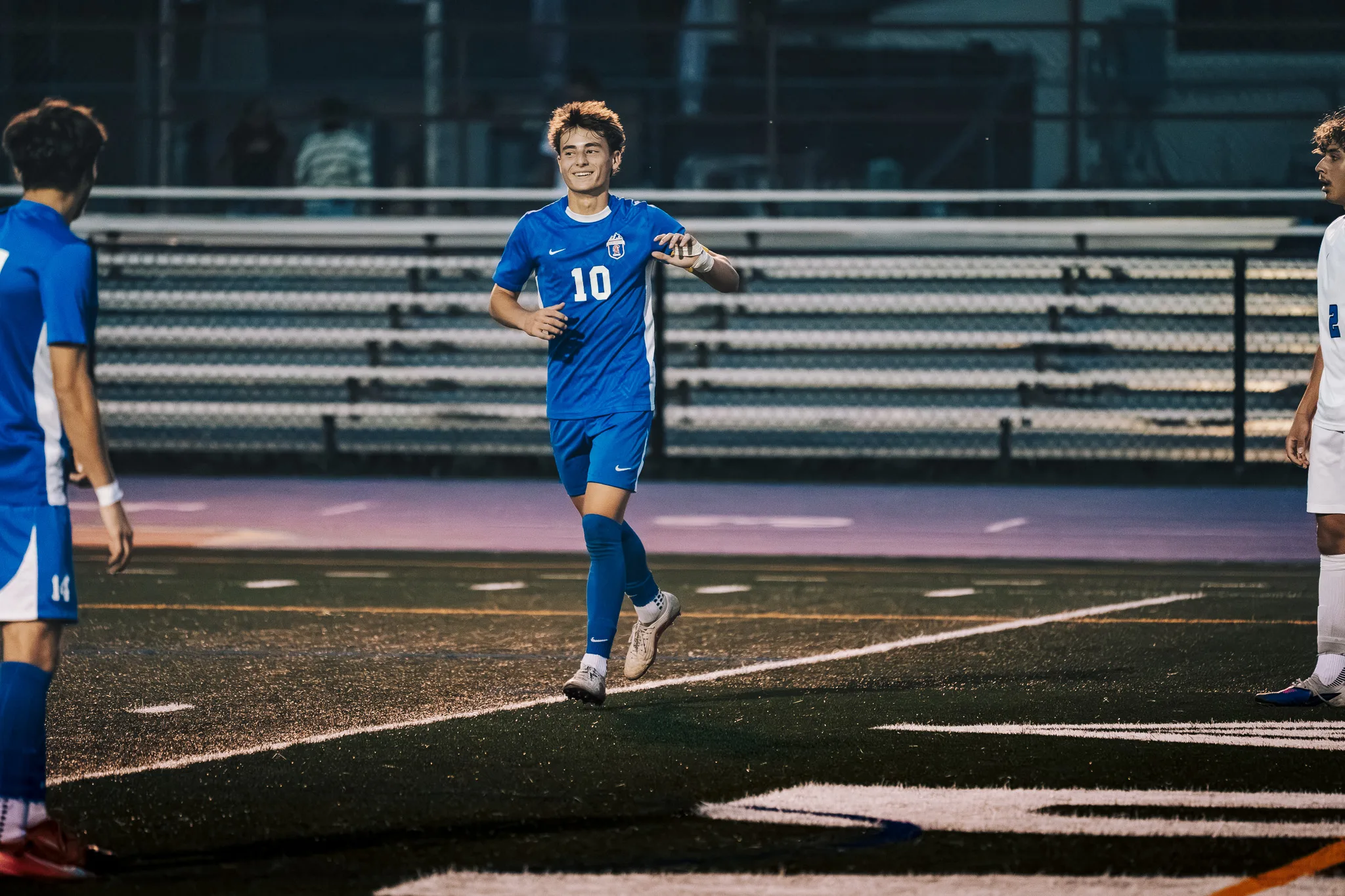 Smiling, Centaurus number 10 jogs toward the camera, Centaurus number 14 at the edge of the frame and the bleachers behind
