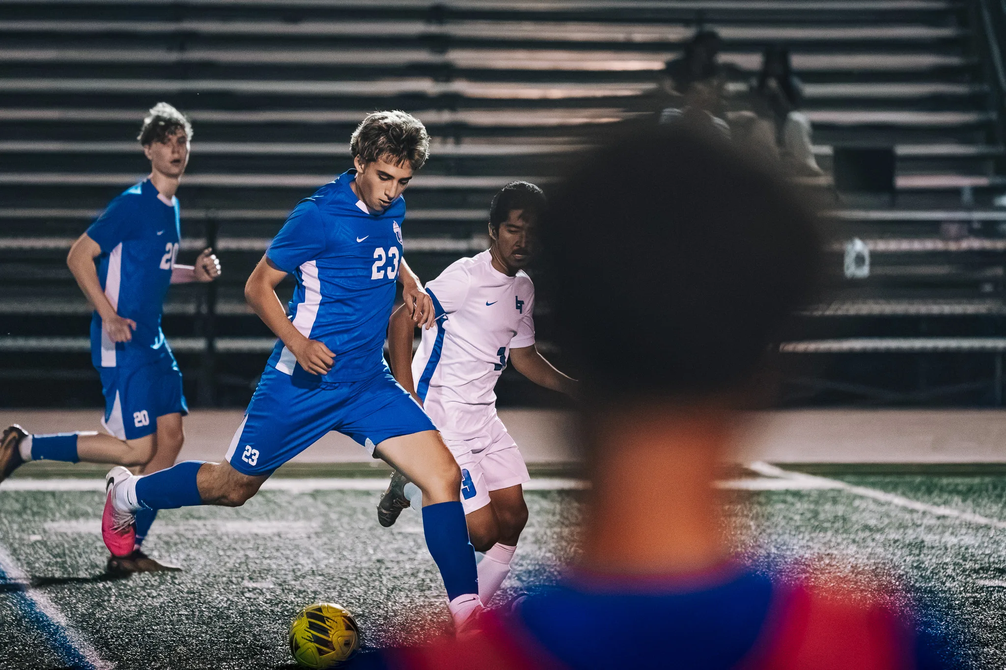 Centaurus number 23 pushes the ball ahead with a Longmont player at his side and Centaurus number 20 nearby