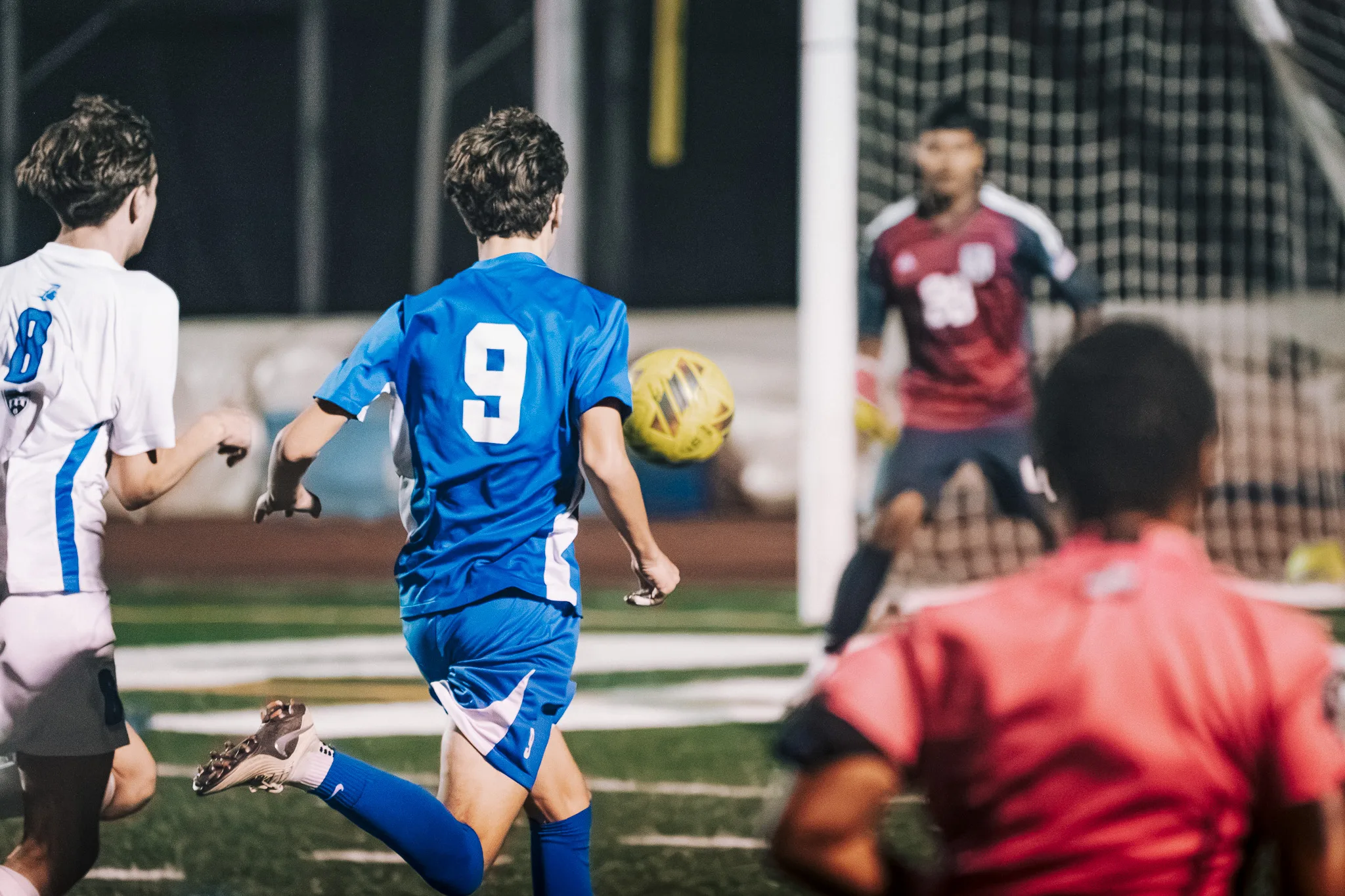 Near the goal, Centaurus number 9 runs after the ball, with Longmont number 8 following and the Longmont goalkeeper waiting