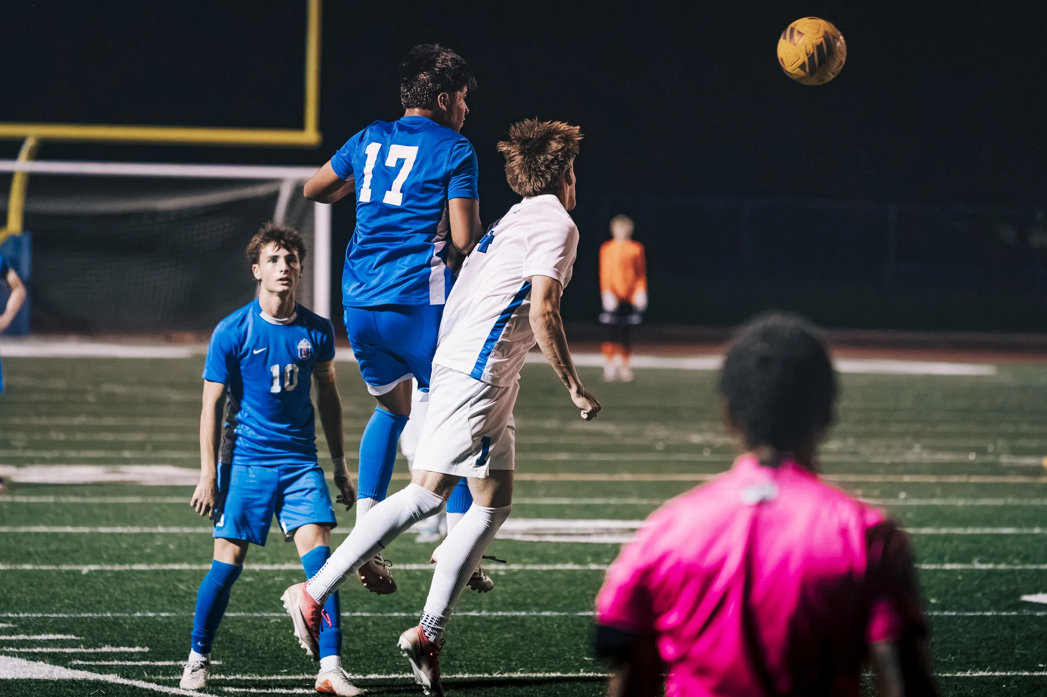 Centaurus number 17 and a Longmont player rise for a header, the ball high above and the Centaurus goalkeeper in orange behind