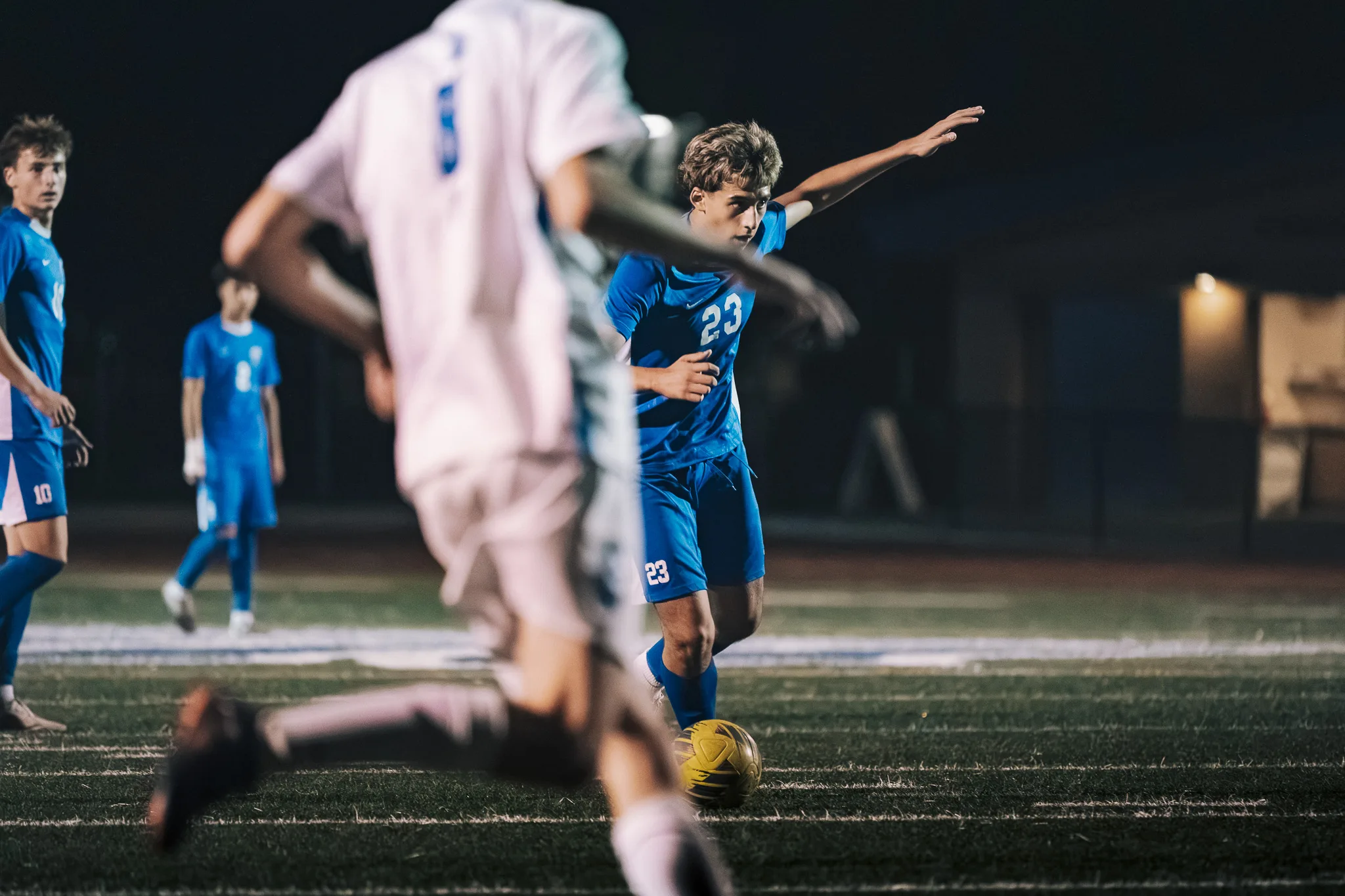 Centaurus number 23 moves in on the ball with one arm stretched out as a blurred Longmont player crosses in front
