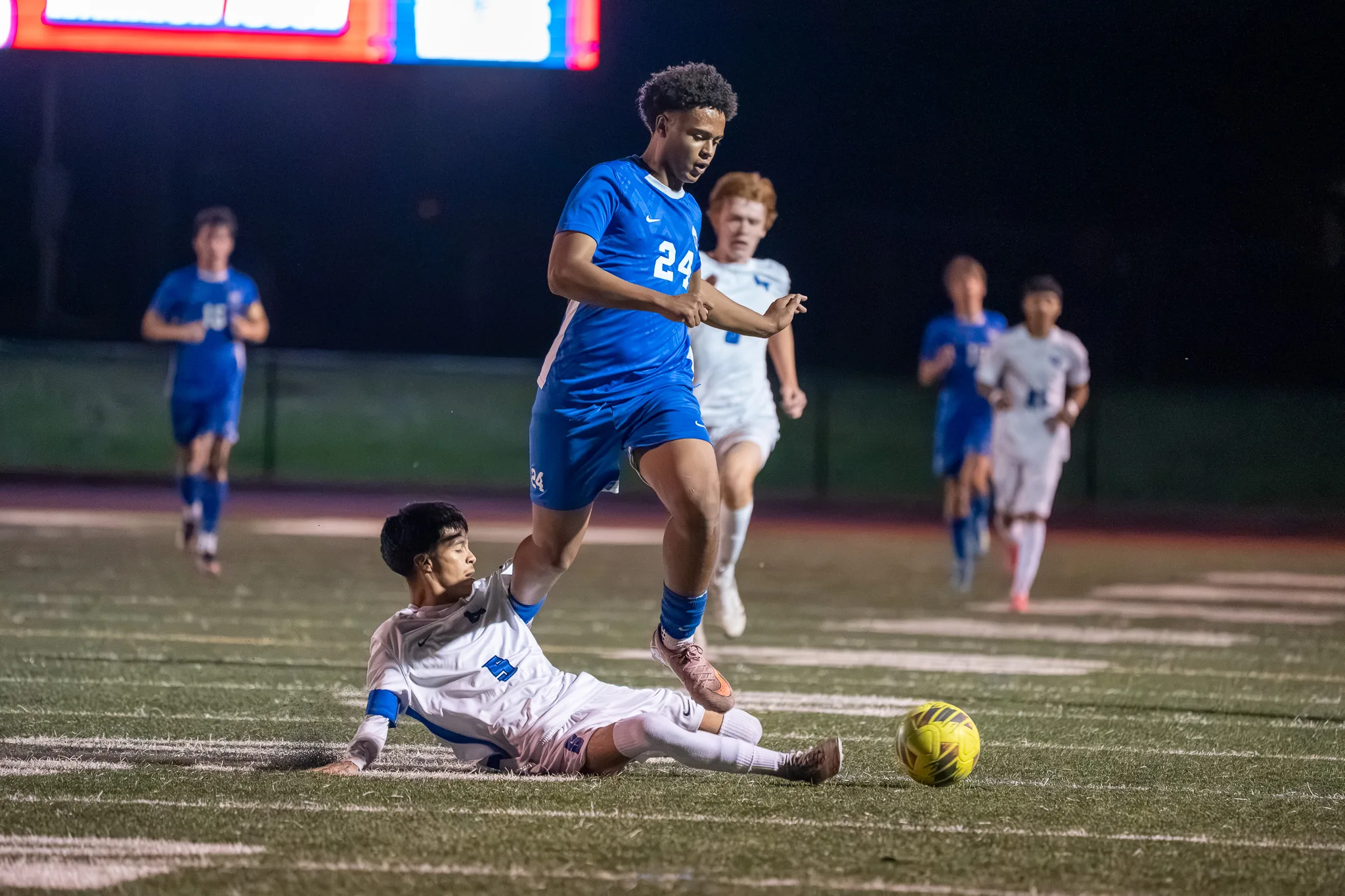 Centaurus number 24 steps over a Longmont player sliding along the turf, the ball just beyond them