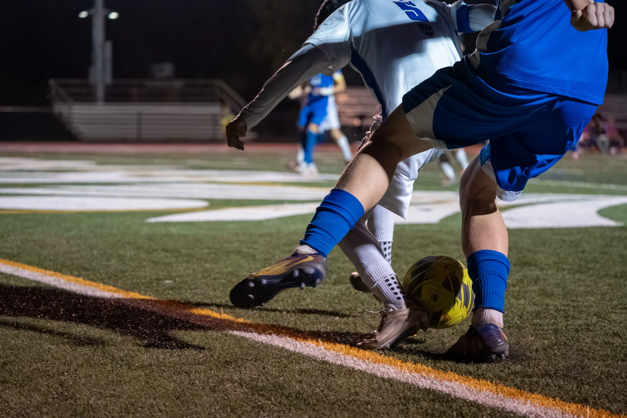 In a close view, legs and cleats tangle over the ball as a Longmont player and a Centaurus player compete beside a painted line