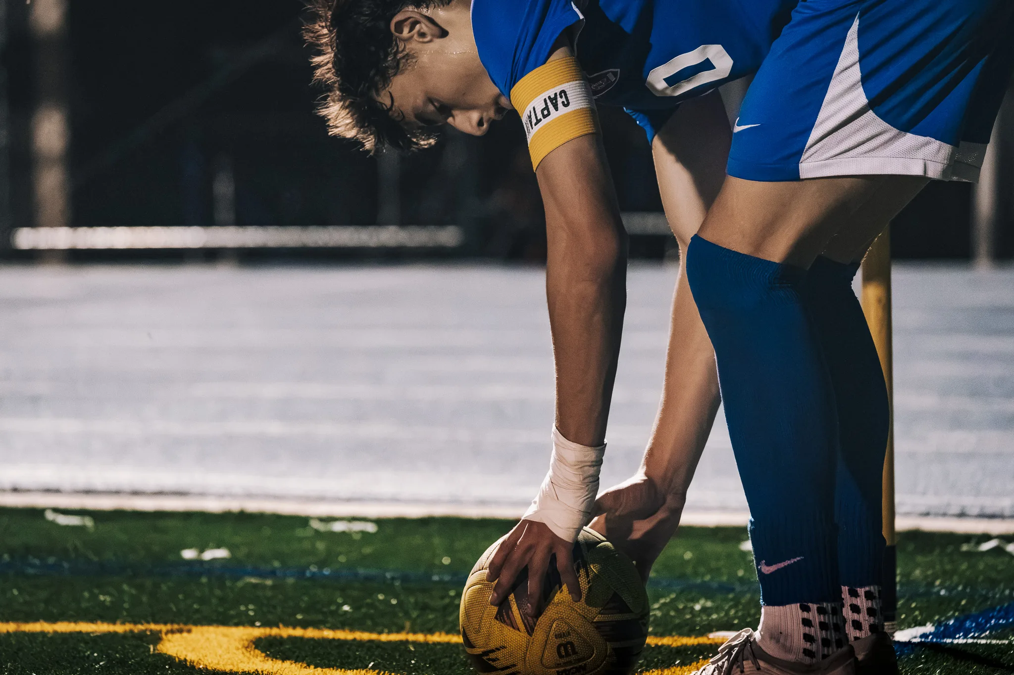A Centaurus captain bends over to set the ball down at the corner of the field, the flag post beside him
