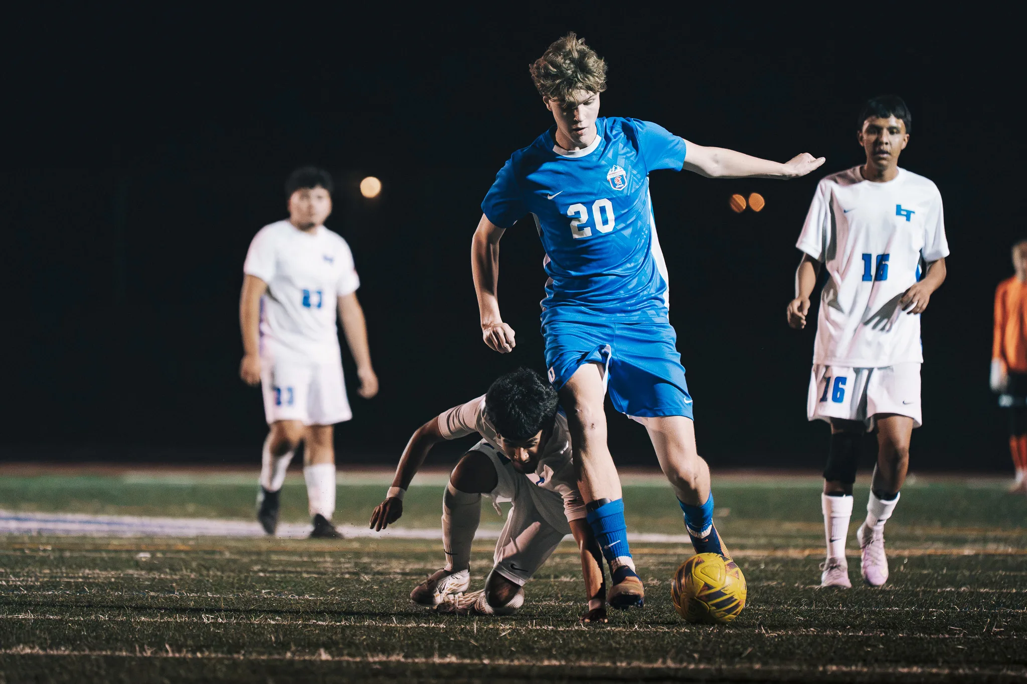 Centaurus number 20 dribbles past a Longmont player down on the turf as Longmont number 16 watches