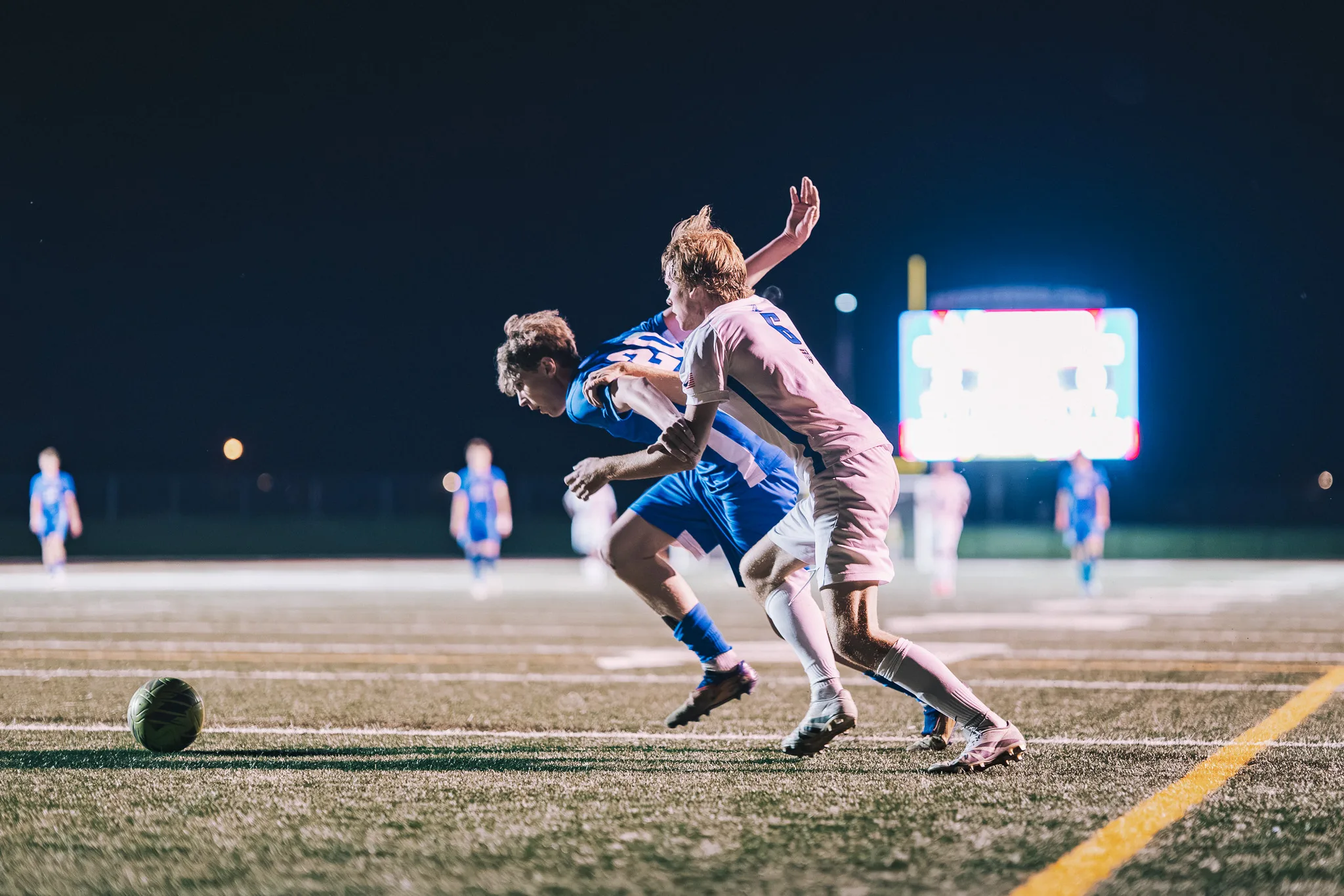 Shoulder to shoulder, a Longmont player and a Centaurus player race toward the ball on the grass ahead