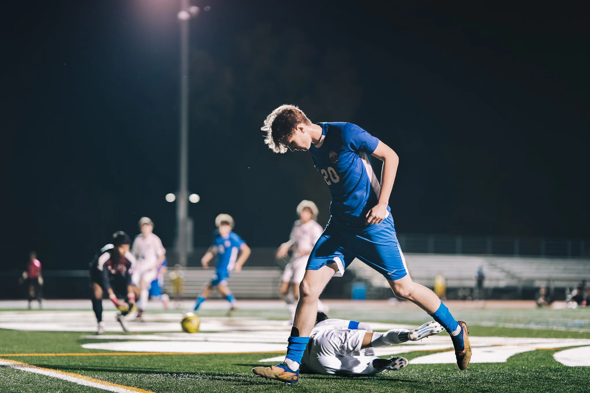 Looking down, Centaurus number 20 steps over a Longmont player lying on the turf, other players behind them