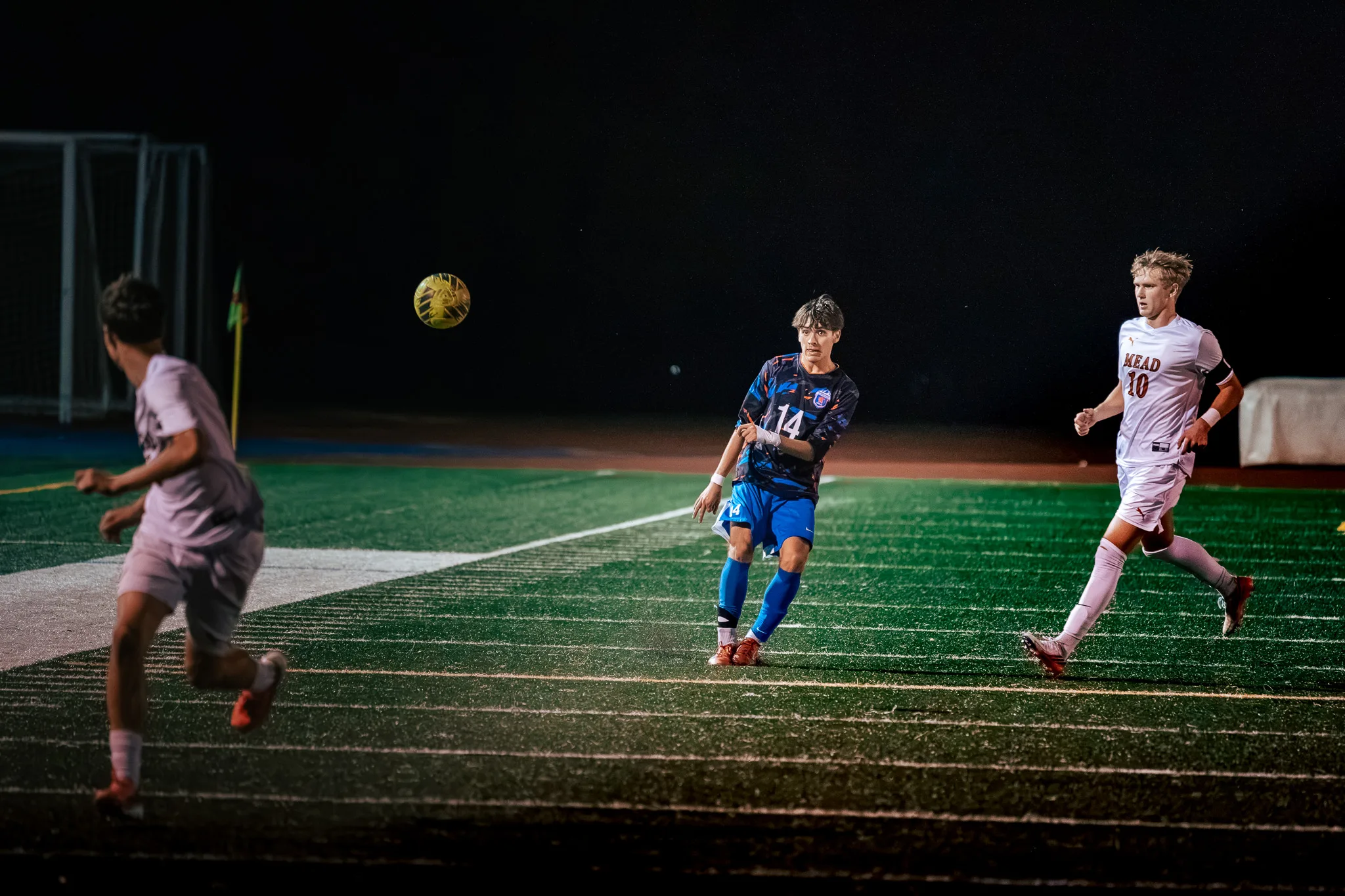 Centaurus number 14 sends the ball away as Mead number 10 runs in from the right and a second Mead player chases from the left