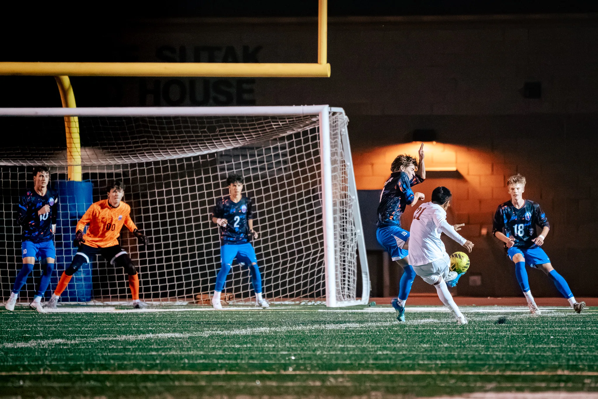 Mead number 21 shoots at the edge of the Centaurus goal as a Centaurus defender leaps at him, with the goalkeeper in orange, number 00, and Centaurus numbers 2 and 18 near the net