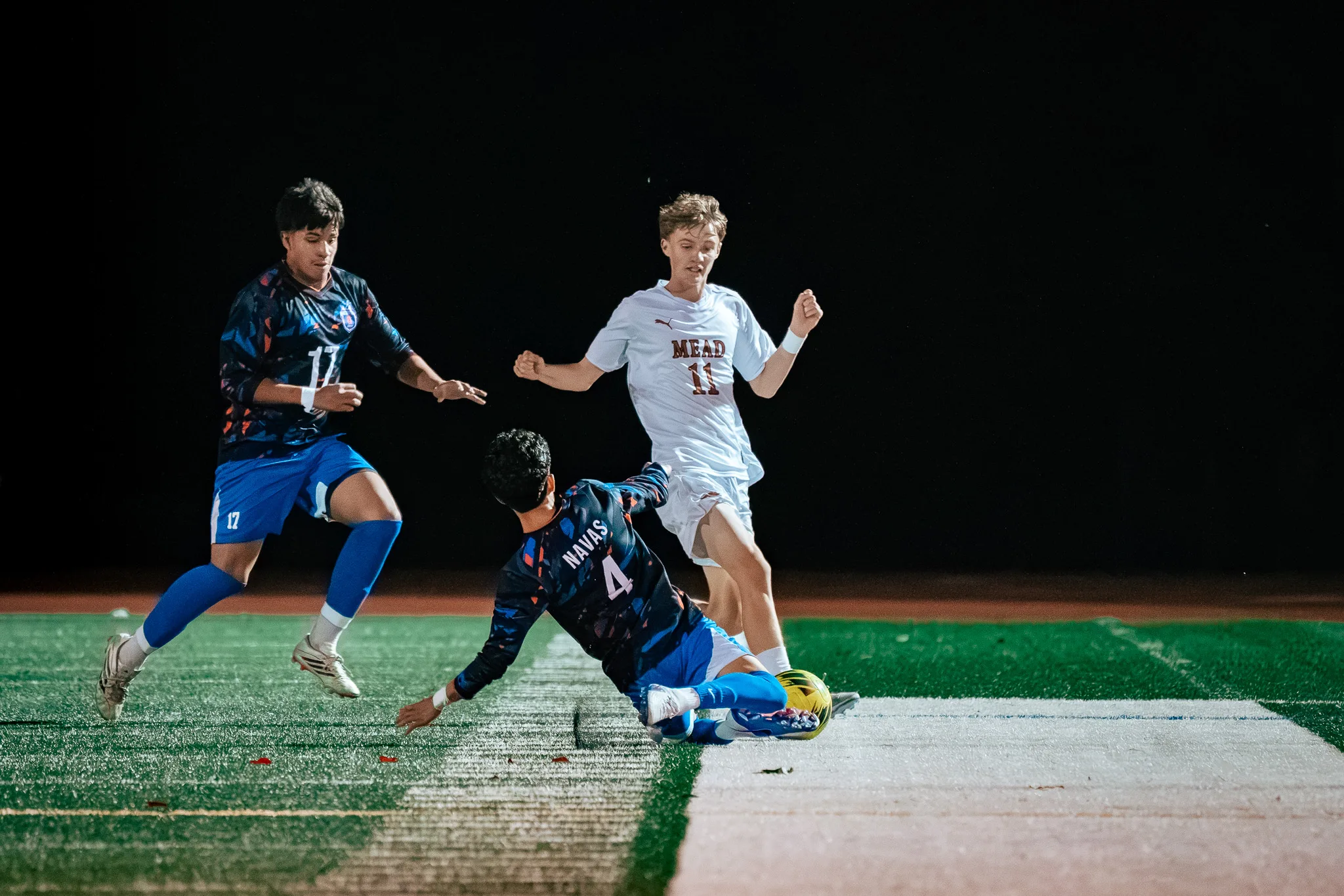 Centaurus number 4 slides in on the ball against Mead number 11 as Centaurus number 17 closes in from the left