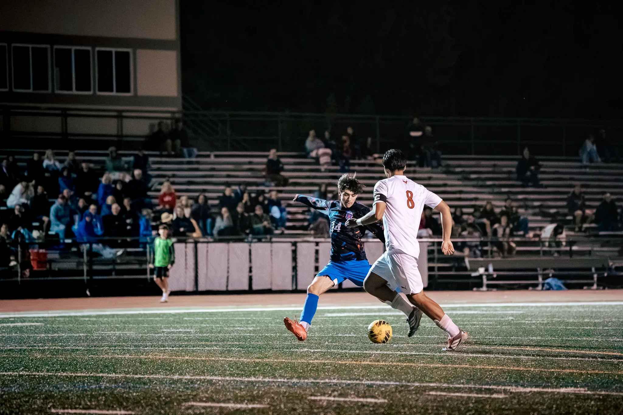Centaurus number 14 and Mead number 8, who wears a captain's armband, chase the ball in front of crowded bleachers