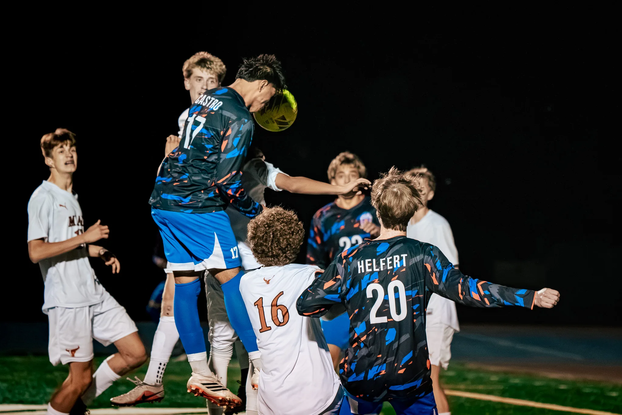 Centaurus number 17 rises above the pack to head the ball as Mead number 16 and Centaurus number 20 jostle beneath him and a Mead player looks on from the left