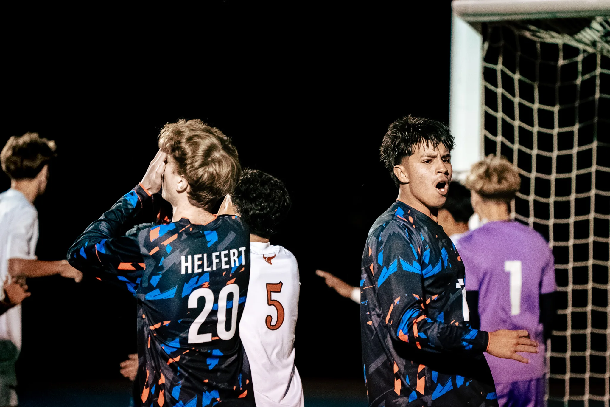 Centaurus number 20 puts a hand to his face beside Mead number 5 as a teammate calls out next to him and the Mead goalkeeper in purple, number 1, stands in front of the net