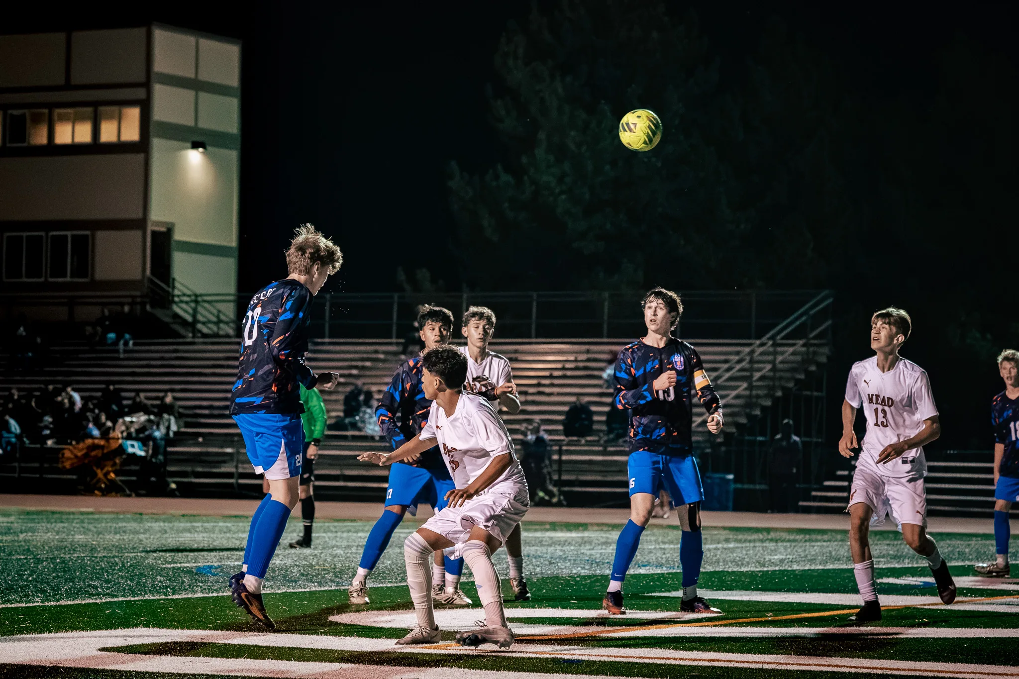 Centaurus number 20 leaps for a header as the ball rises above a crowd of players from both teams, with Mead number 13 watching from the right