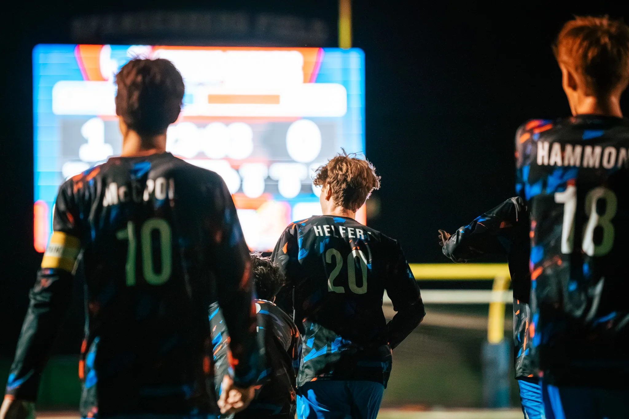 Seen from behind, Centaurus numbers 10, 20 and 18 walk toward the glowing scoreboard, which reads 1 to 0
