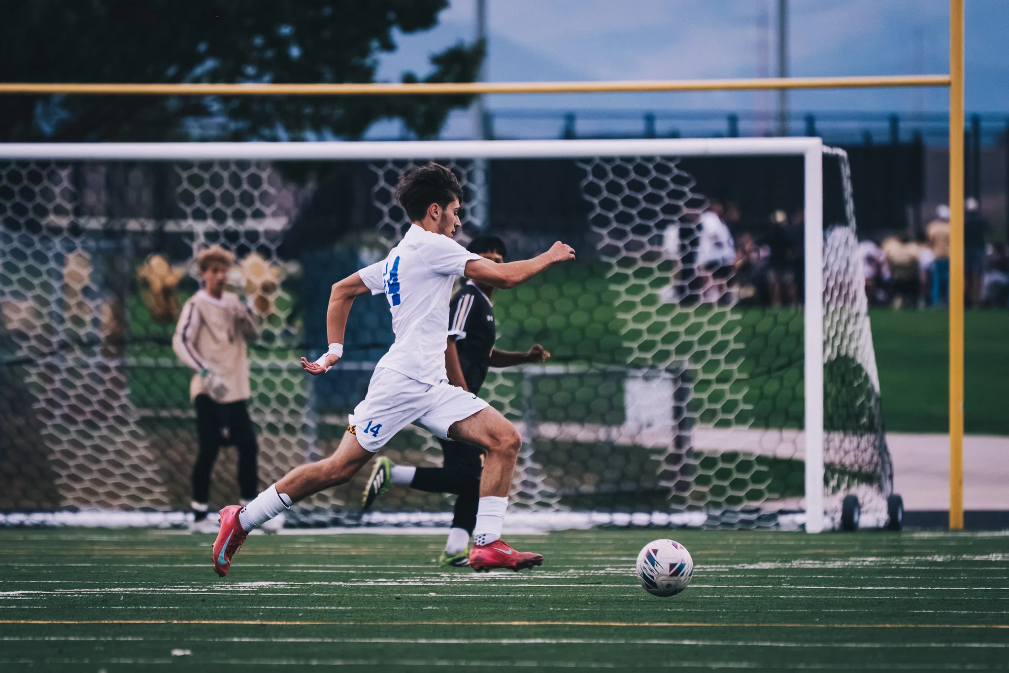 Centaurus number 14 strides onto the ball in front of the goal, a Monarch defender at his back