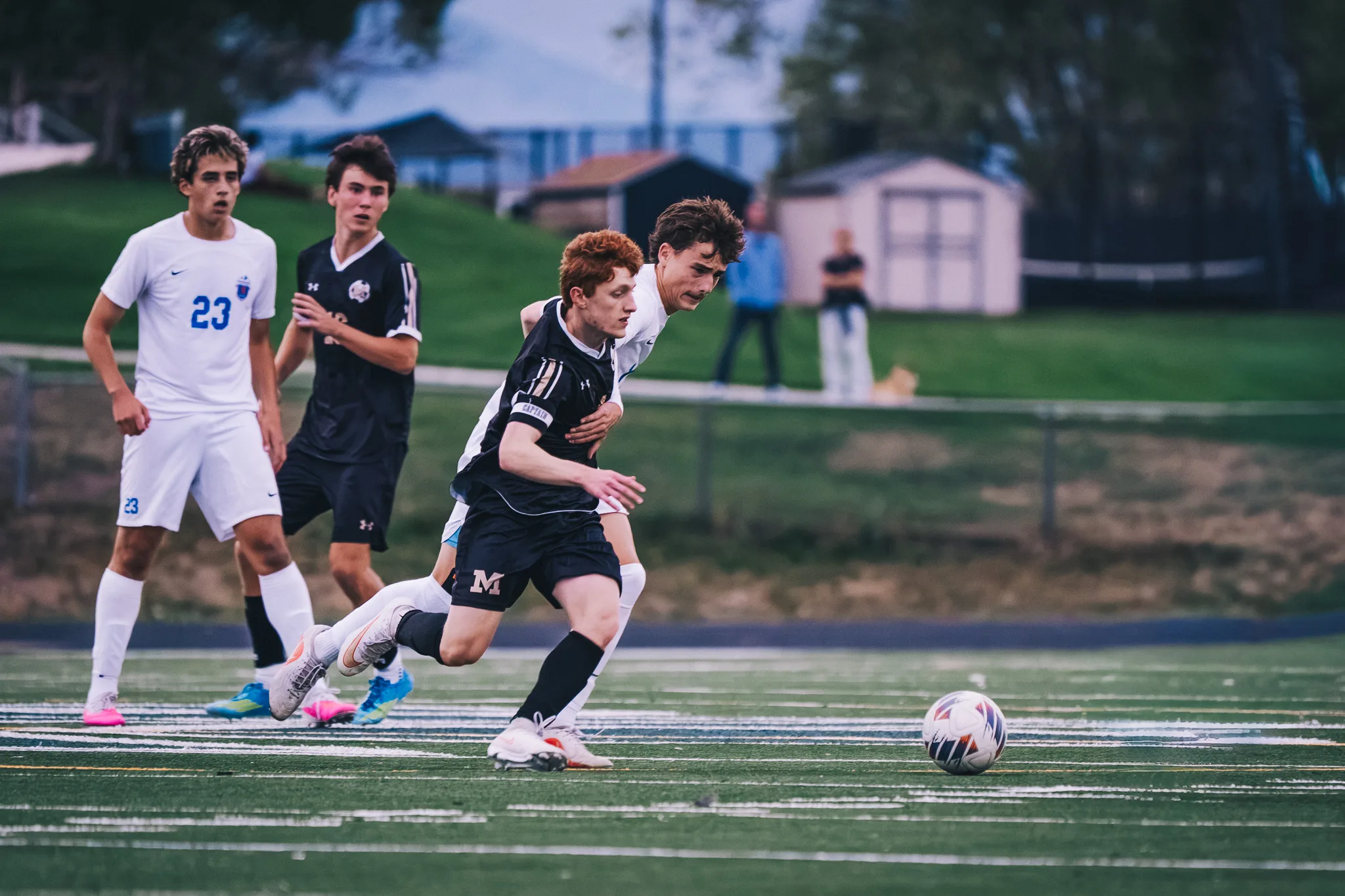 A Monarch player in black races a Centaurus player to the loose ball, with Centaurus number 23 behind them