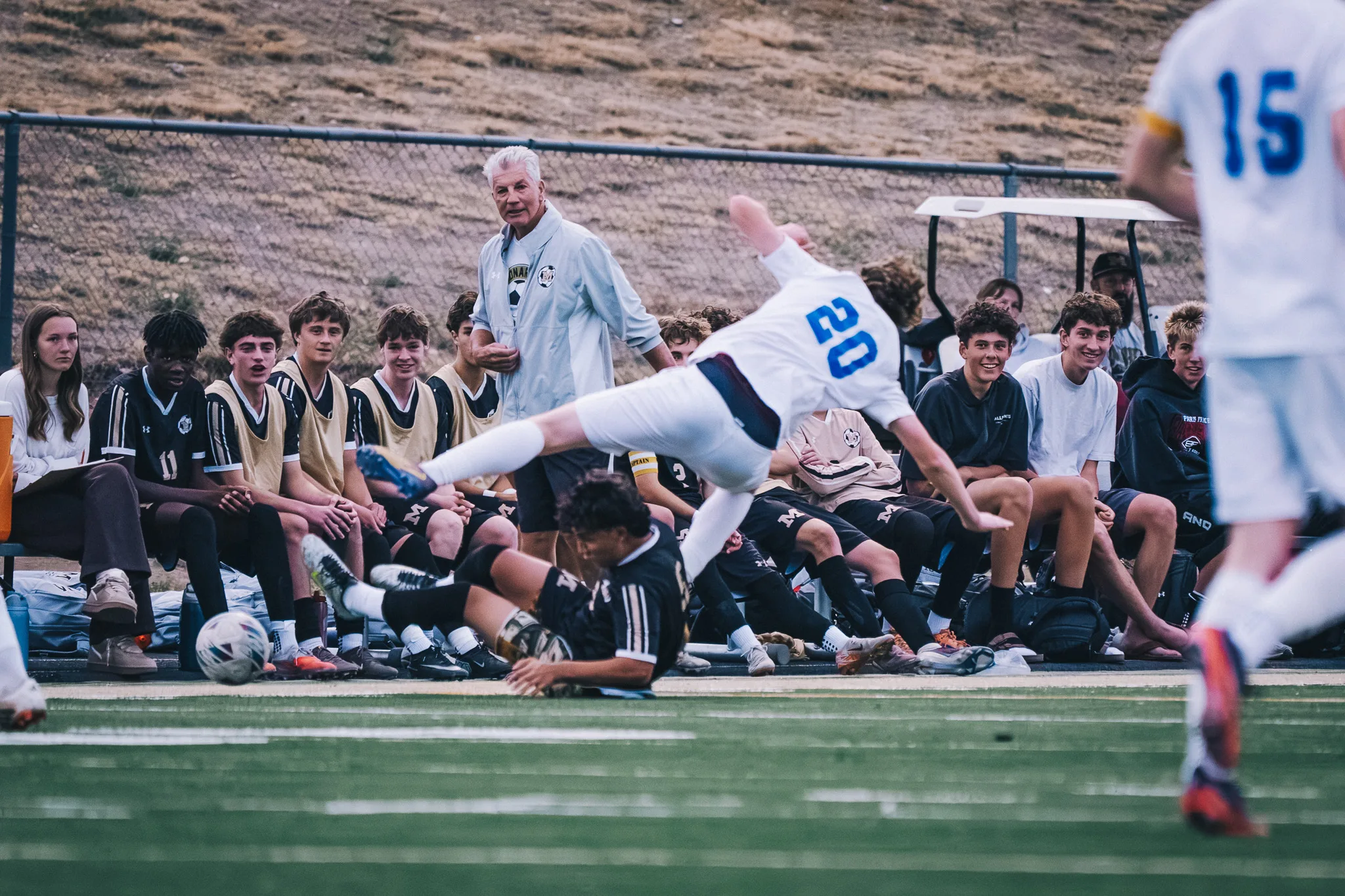 Centaurus number 20 tumbles over a sliding Monarch player in front of the Monarch bench