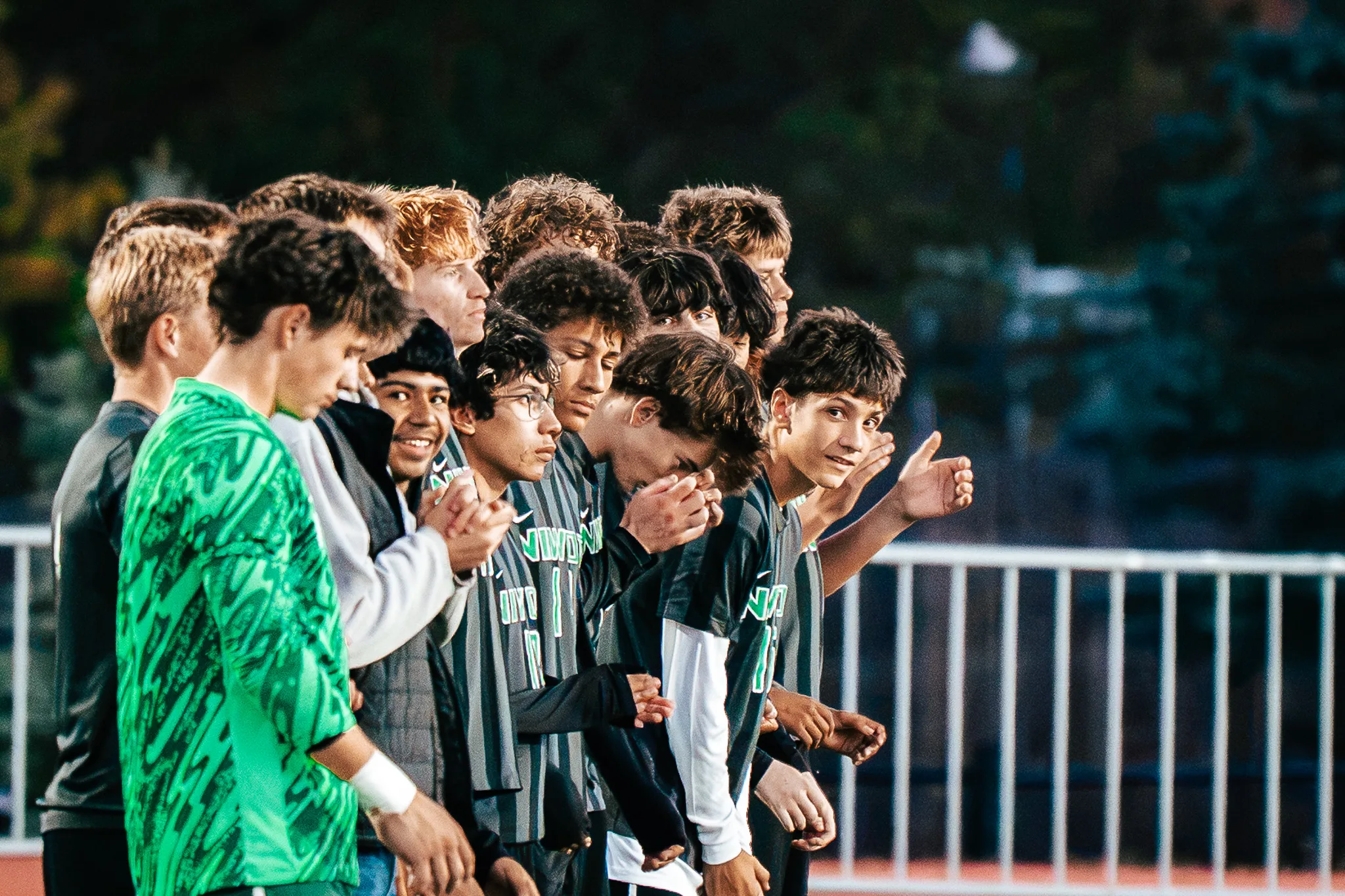 Before kickoff, Niwot players stand in a line beside their goalkeeper in green, some smiling, one holding out his hand