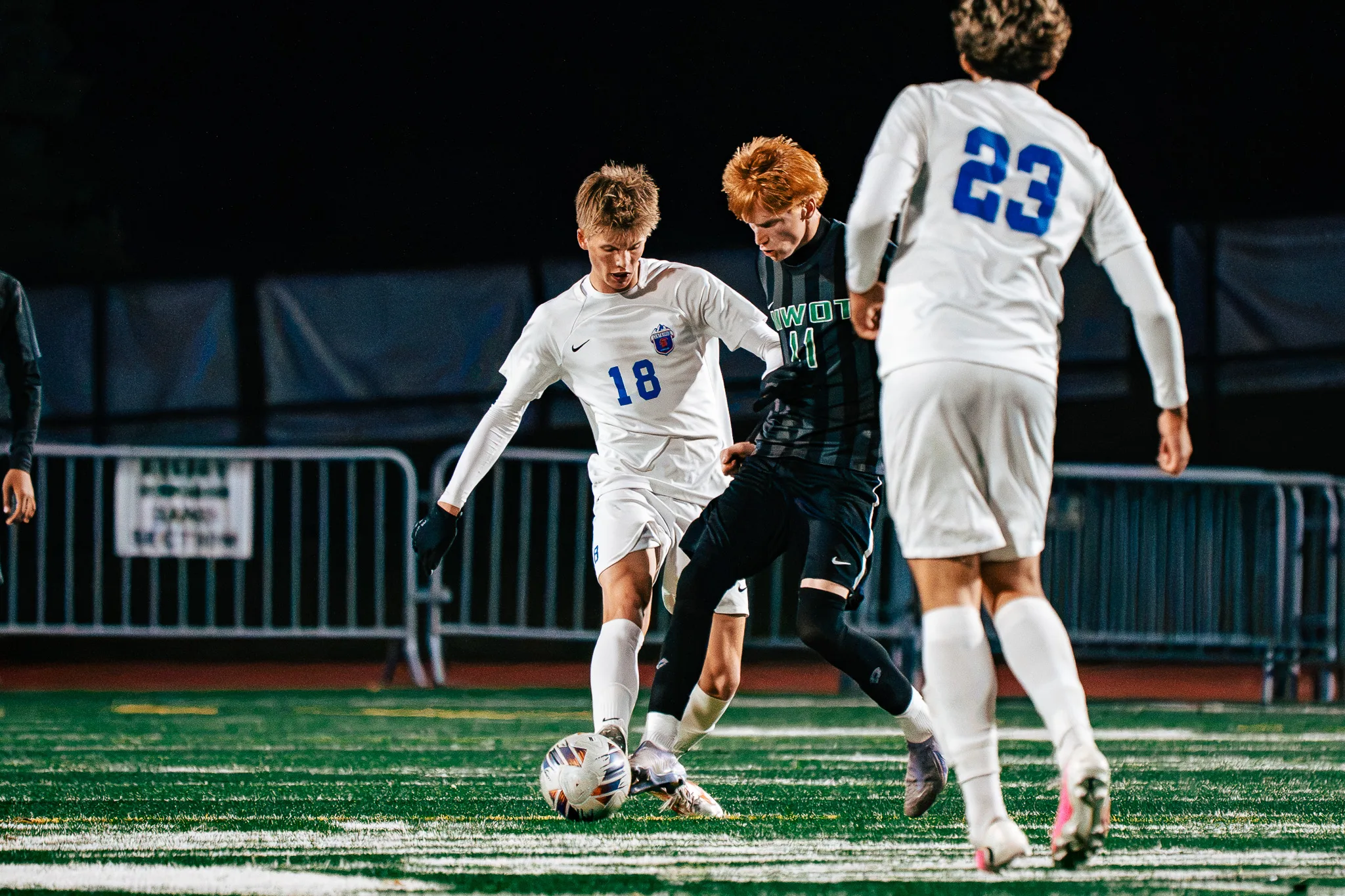 Centaurus number 18 and Niwot number 11, who has red hair, fight for the ball at their feet as Centaurus number 23 closes in from behind